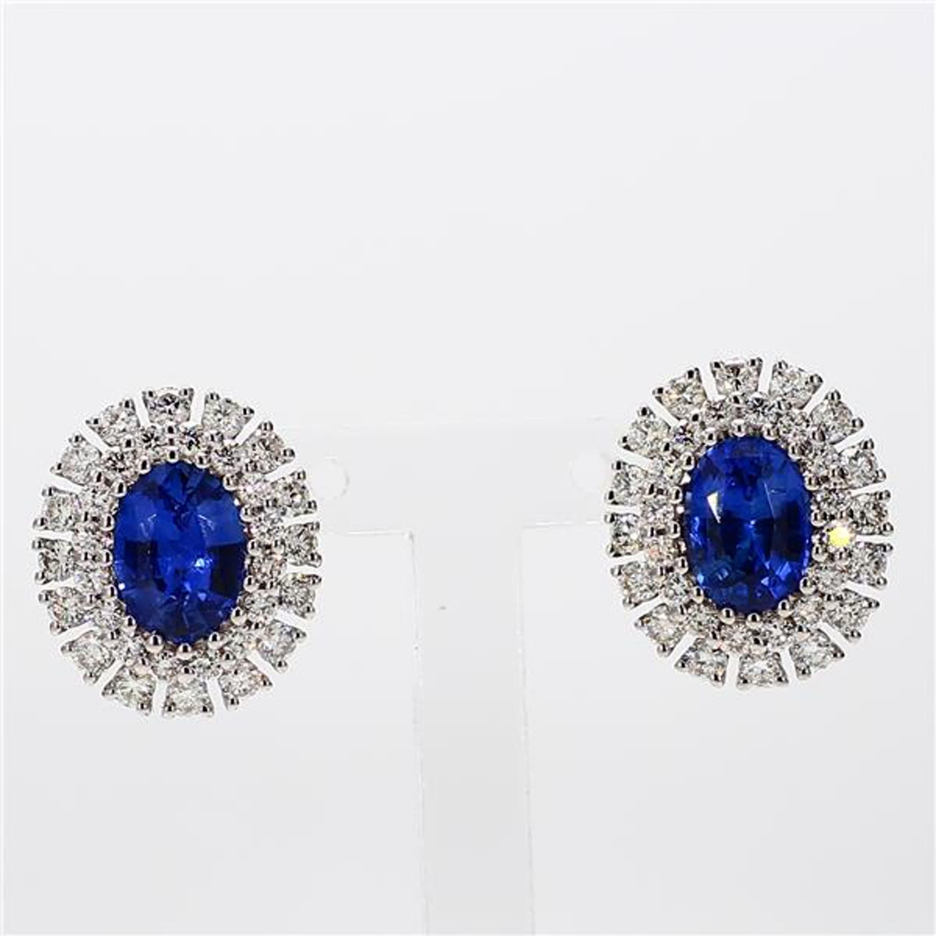 RareGemWorld's classic sapphire earrings. Mounted in a beautiful 18K White Gold setting with natural oval cut blue sapphires. The sapphires are surrounded by natural round white diamond melee. These earrings are guaranteed to impress and enhance