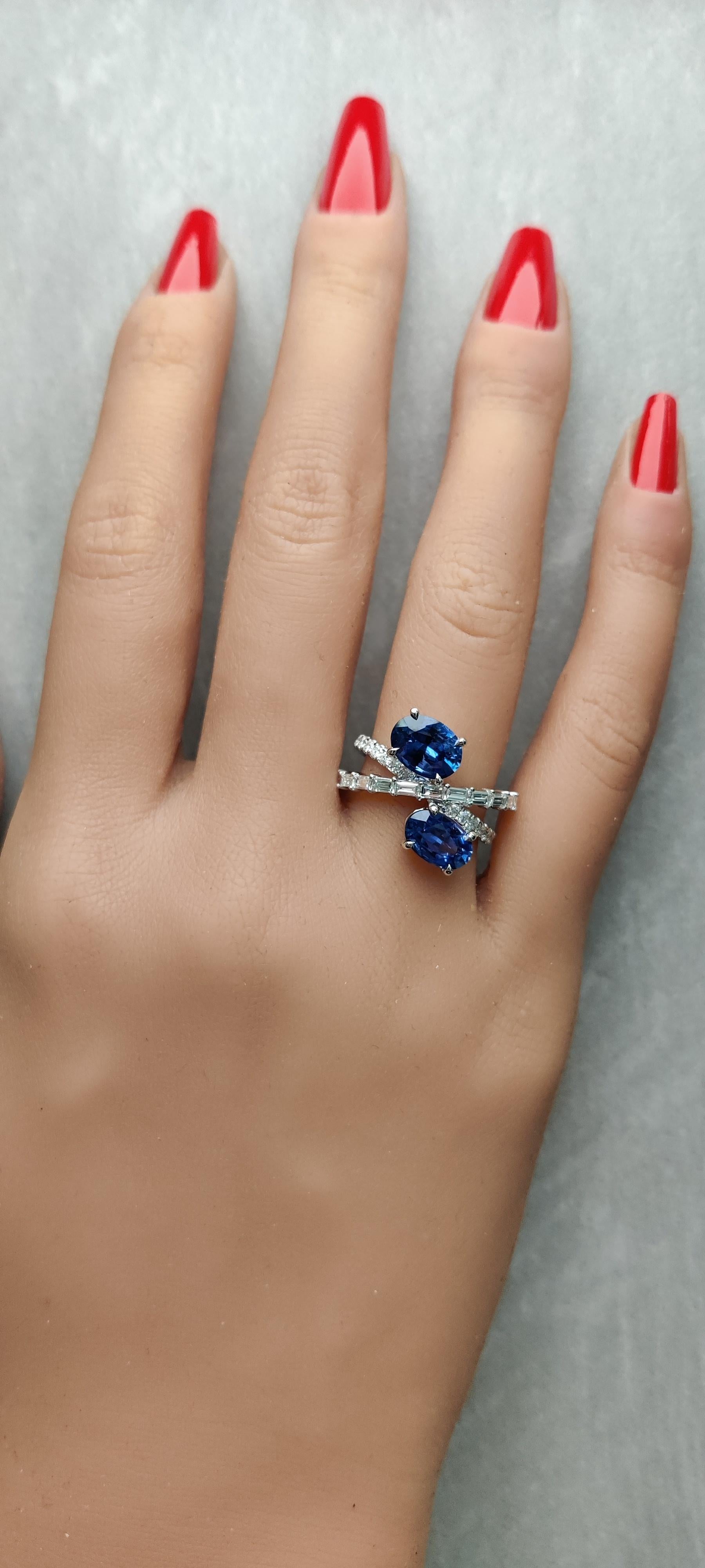 RareGemWorld's classic sapphire ring. Mounted in a beautiful 18K White Gold setting with two natural oval cut blue sapphire. The sapphire is surrounded by natural baguette cut white diamond and round natural white diamond melee. This ring is