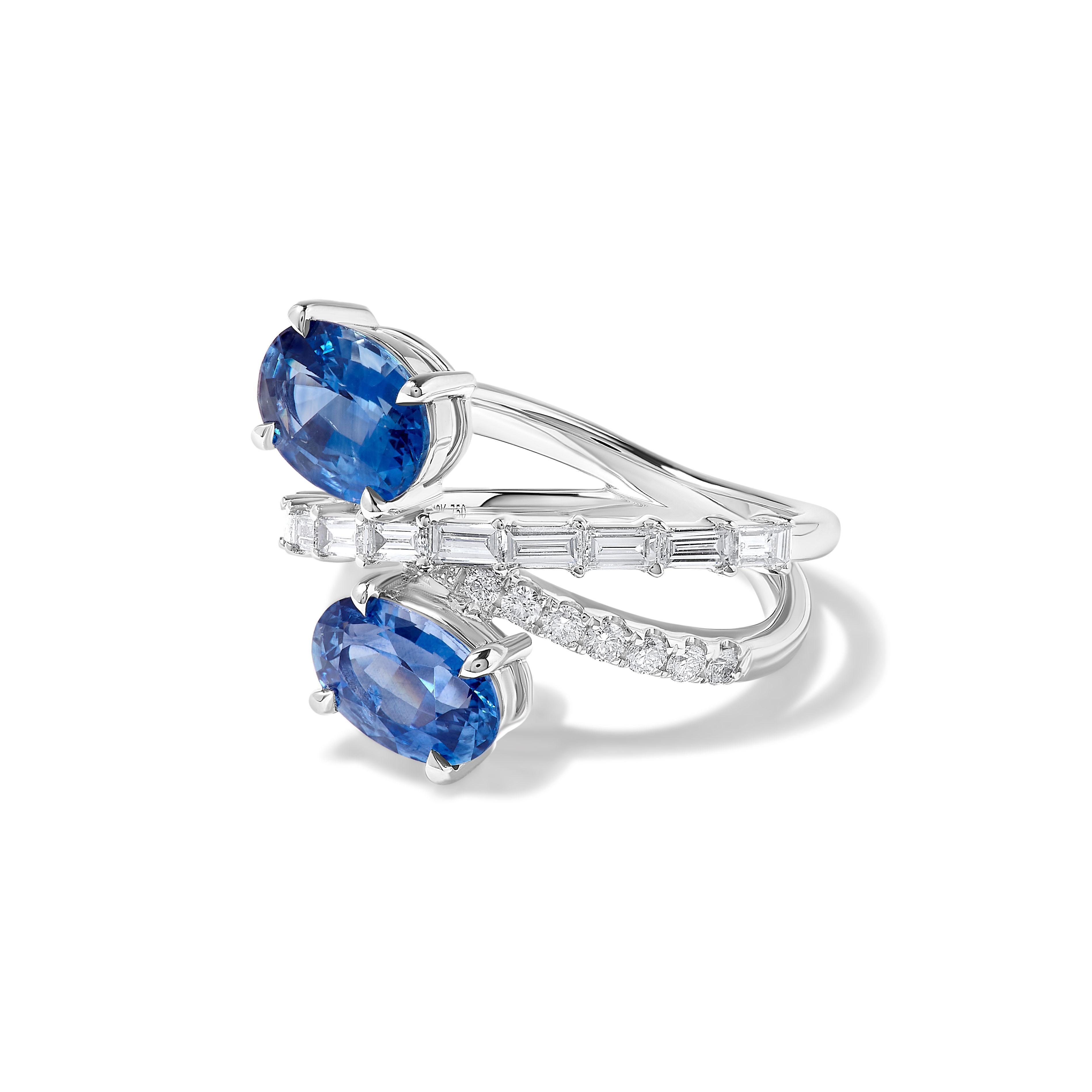La magnifique bague en saphir de Raregemworld. Montée dans une belle monture en or blanc 18 carats avec deux saphirs bleus naturels de taille ovale. Le saphir est entouré d'un diamant blanc de taille baguette et d'un diamant blanc rond. Cette bague