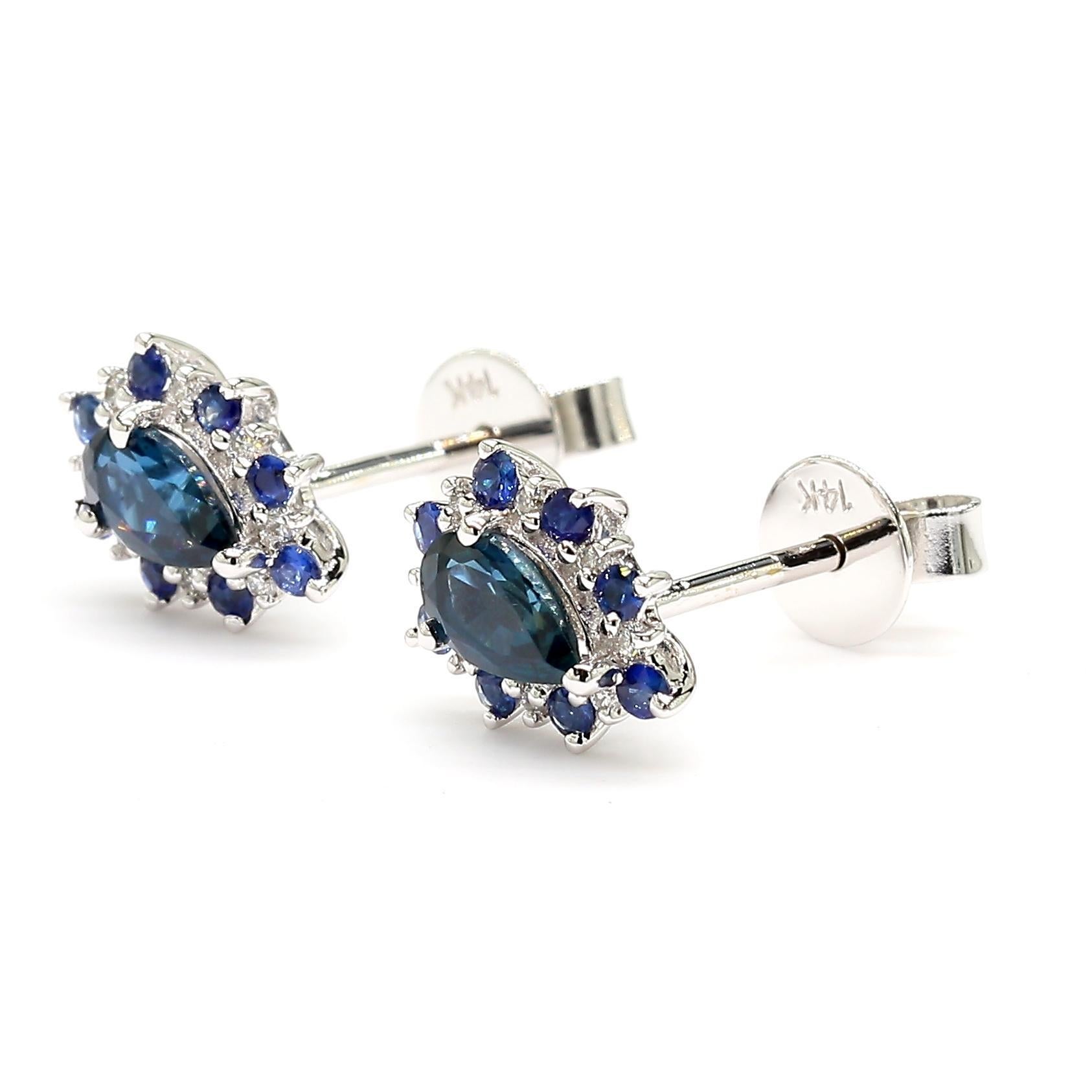 RareGemWorld's intriguing sapphire earrings. Mounted in a beautiful 14K White Gold setting with natural pear cut blue sapphires. The sapphires are surrounded by natural round cut blue sapphires and natural round white diamond melee. These earrings
