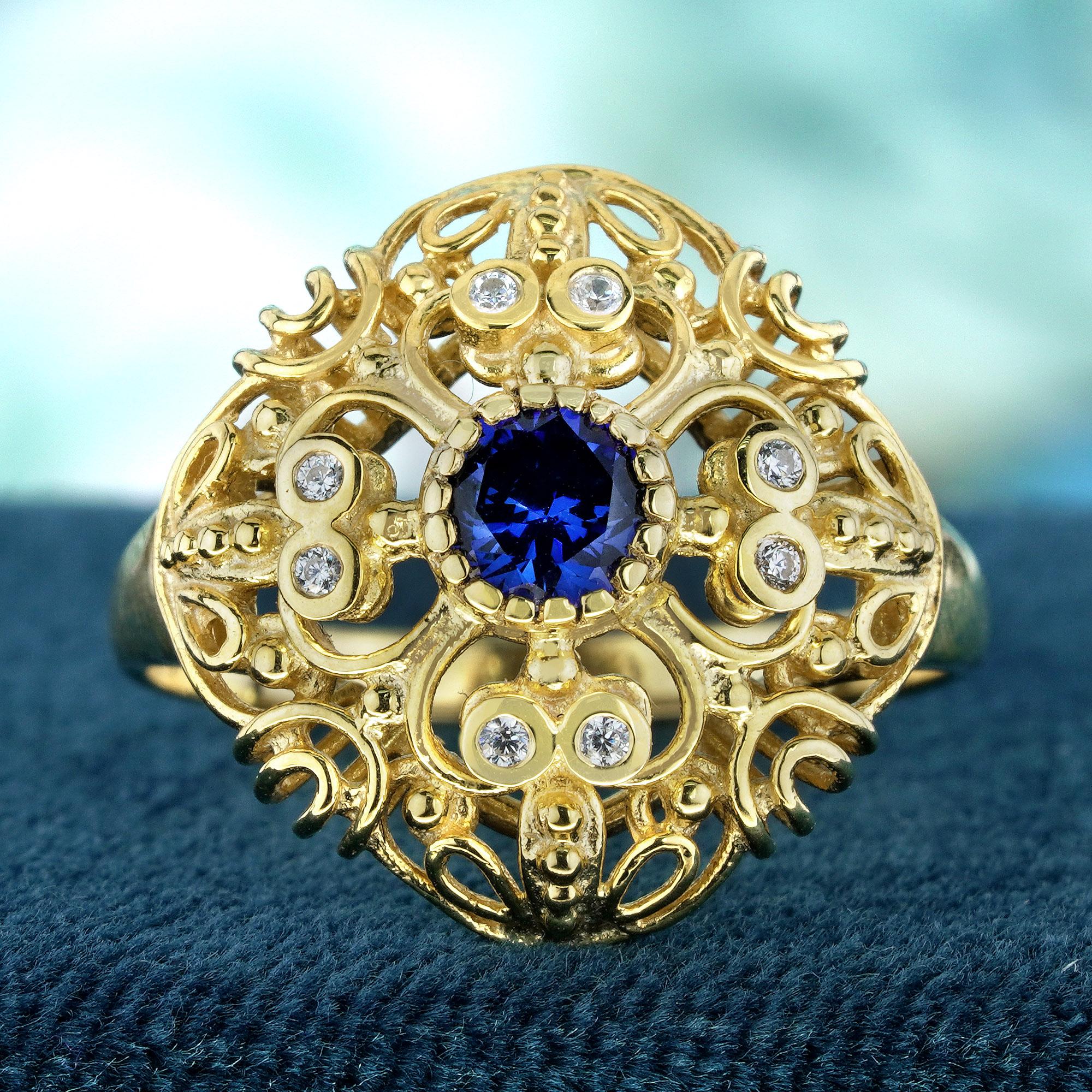 The central round blue sapphire of this vintage-inspired ring is accentuated by the stunning intricate filigree work and the brilliance of the embedded diamonds. The yellow gold band enhances the overall vintage aesthetic, making it a sophisticated