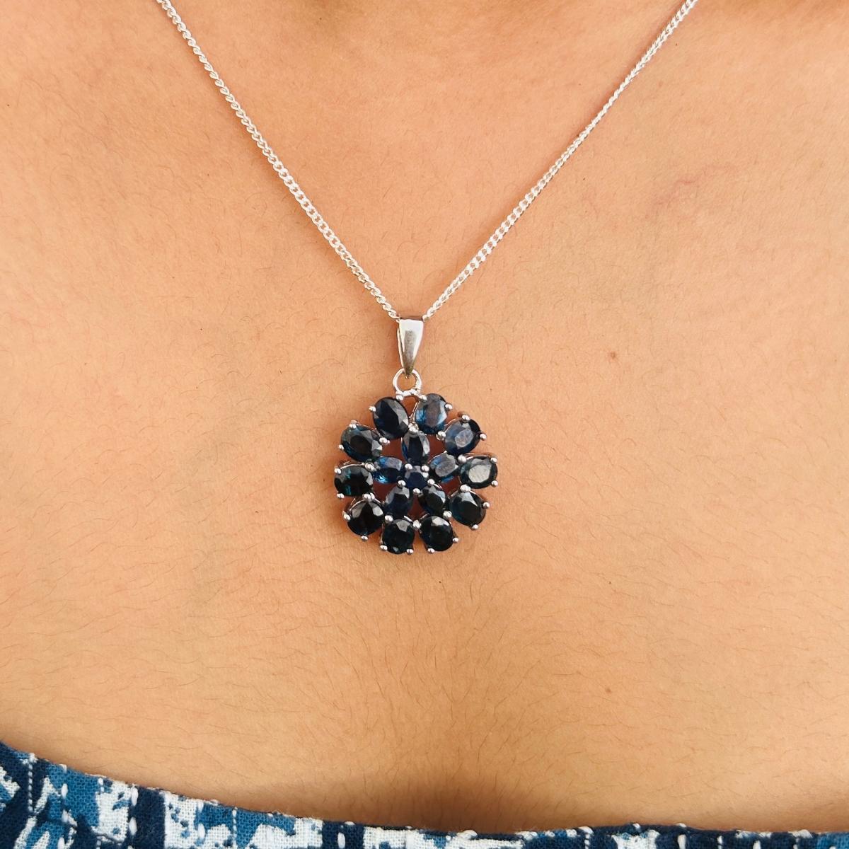 Ciondolo fiore di zaffiro blu naturale in argento sterling con zaffiro blu rotondo e ovale. Questo splendido gioiello eleva immediatamente un look casual o un abito elegante. 
Lo Zaffiro blu aumenta le capacità intellettuali della persona.
Disegnato