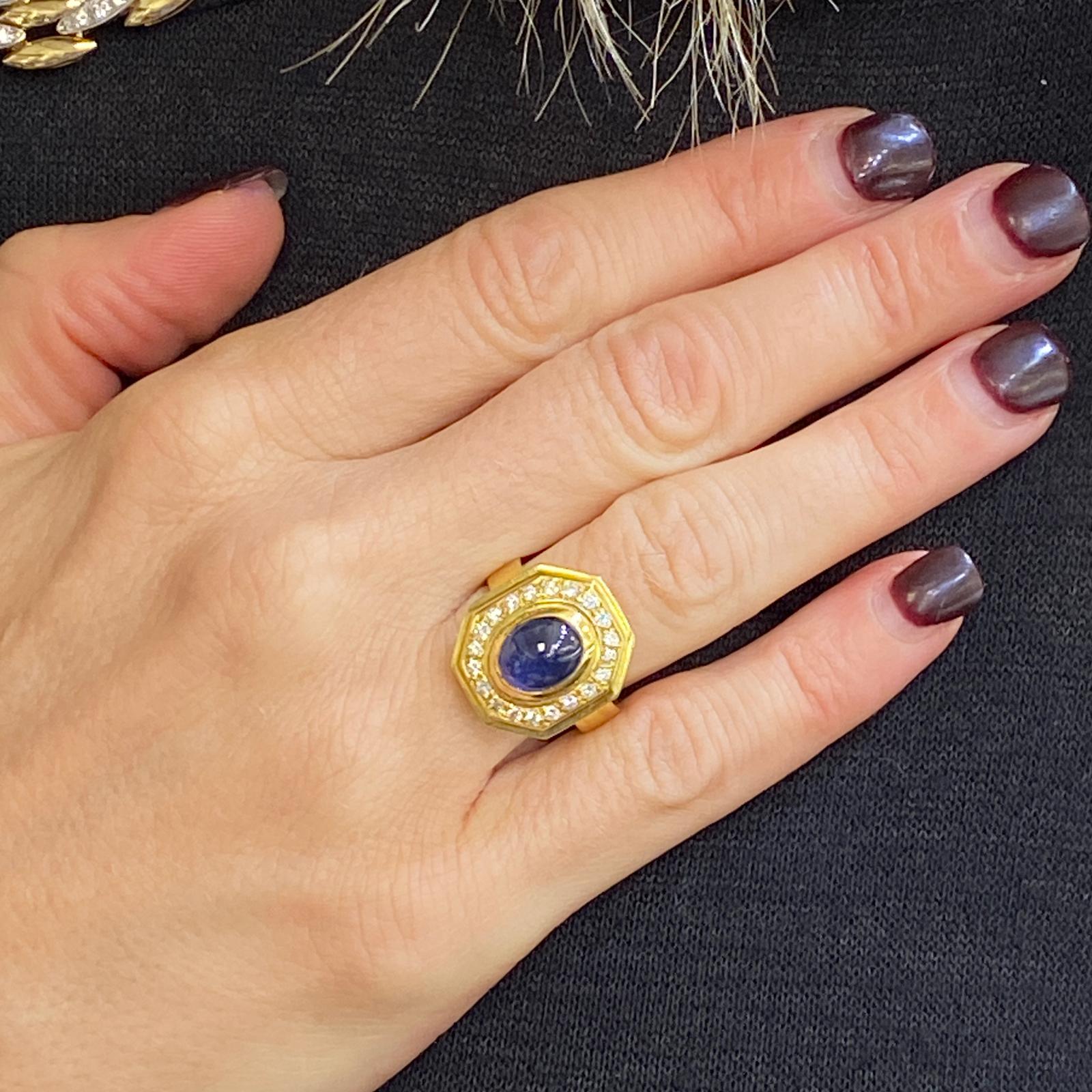 Bright blue sapphire diamond ring fashioned in 18 karat yellow gold. The ring features a 2.60 carat cabochon natural blue sapphire surrounded by 20 round brilliant cut diamonds weighing approximately .40 carat total weight. The high quality diamonds
