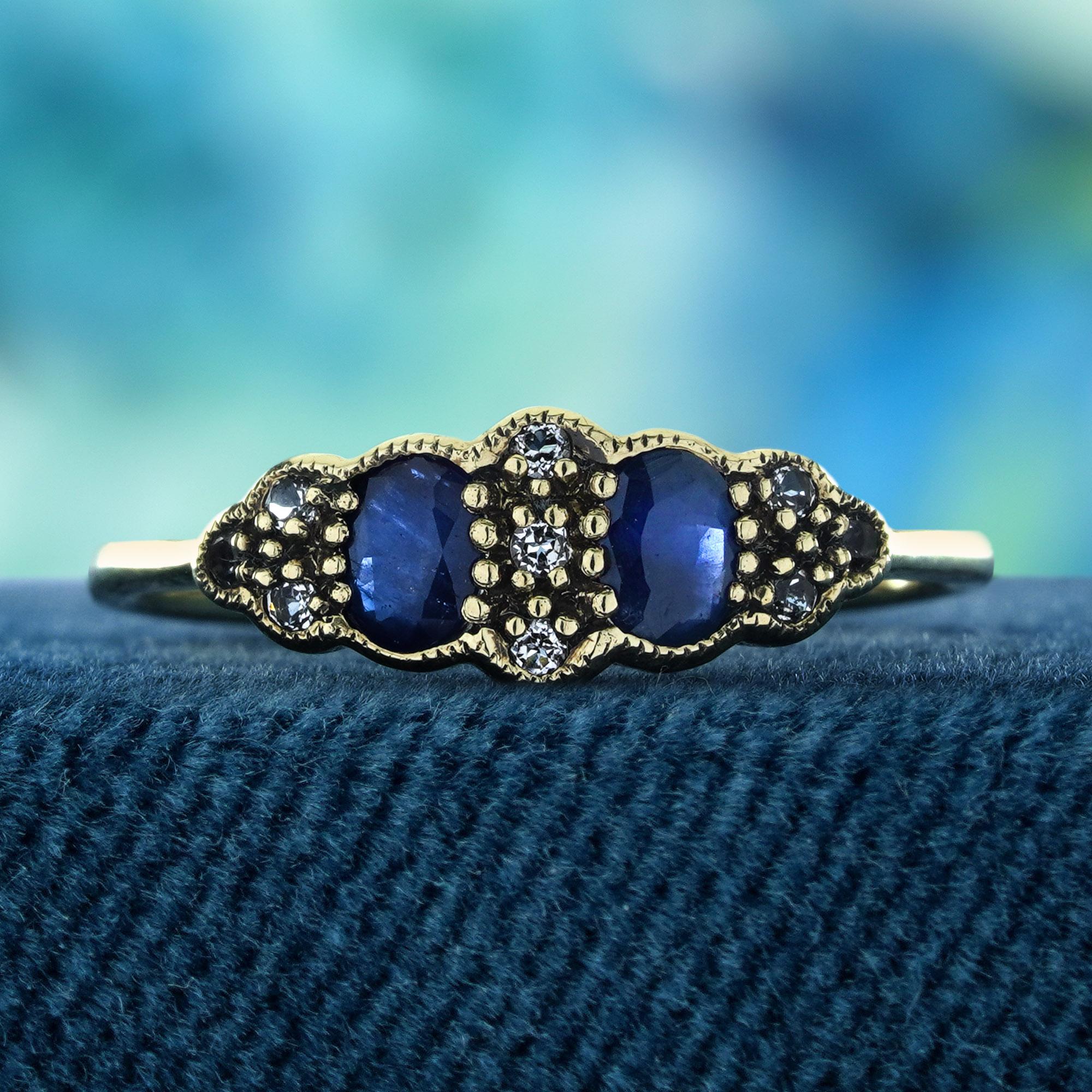 Dieser exquisite Ring mit zwei Steinen aus blauem Saphir und Diamant im Vintage-Stil aus 9-karätigem Gelbgold zeichnet sich durch zwei atemberaubende ovale blaue Saphire aus, die wunderschön von funkelnden Diamanten eingerahmt werden. Das zarte