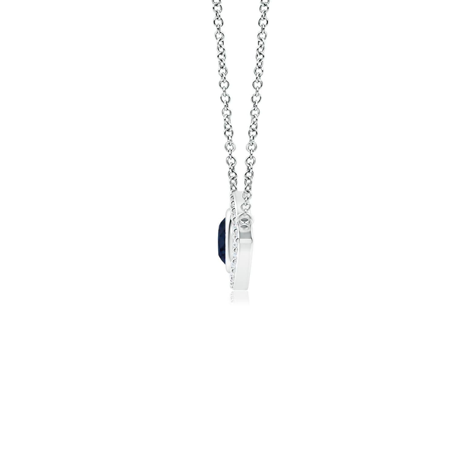 Hanging gracefully from a shiny metal bale is a diamond studded frame with a round sapphire bezel set at the center. The sparkling diamonds create a compelling contrast against the deep blue sapphire. Crafted in 14k white gold, this sapphire evil