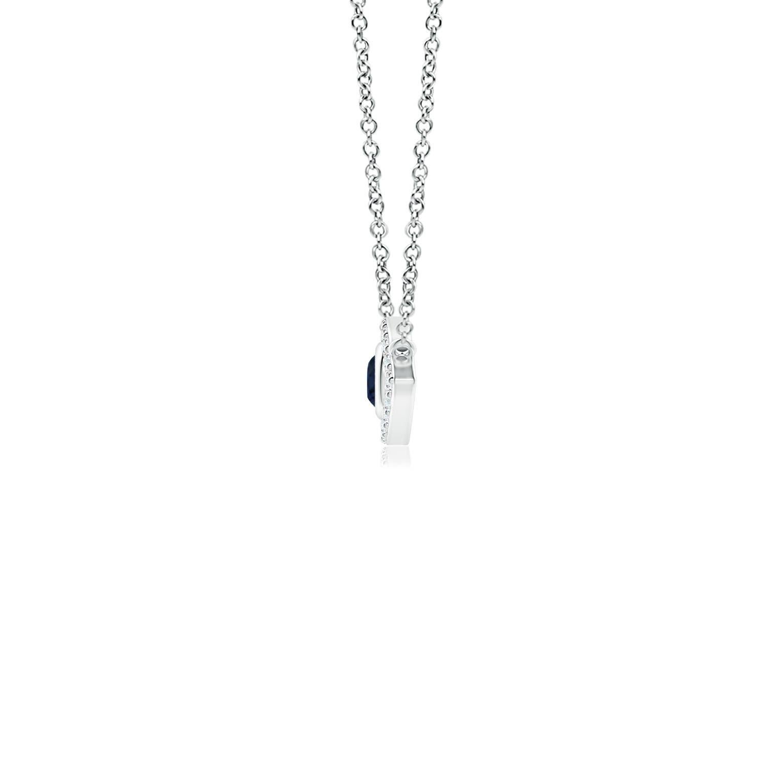 Hanging gracefully from a shiny metal bale is a diamond studded frame with a round sapphire bezel set at the center. The sparkling diamonds create a compelling contrast against the deep blue sapphire. Crafted in 18k white gold, this sapphire evil