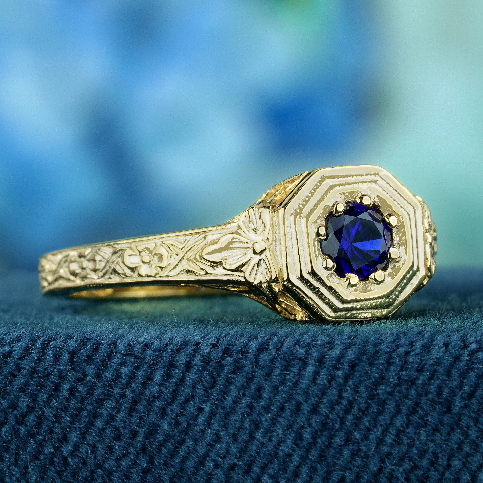Das Gelbgoldband und die Fassung sind mit komplizierten floralen Schnitzereien versehen, die den antiken Charme des Rings unterstreichen. In seinem Zentrum befindet sich ein blauer Saphir, der in einem sechseckigen Rahmen gefasst ist und einen