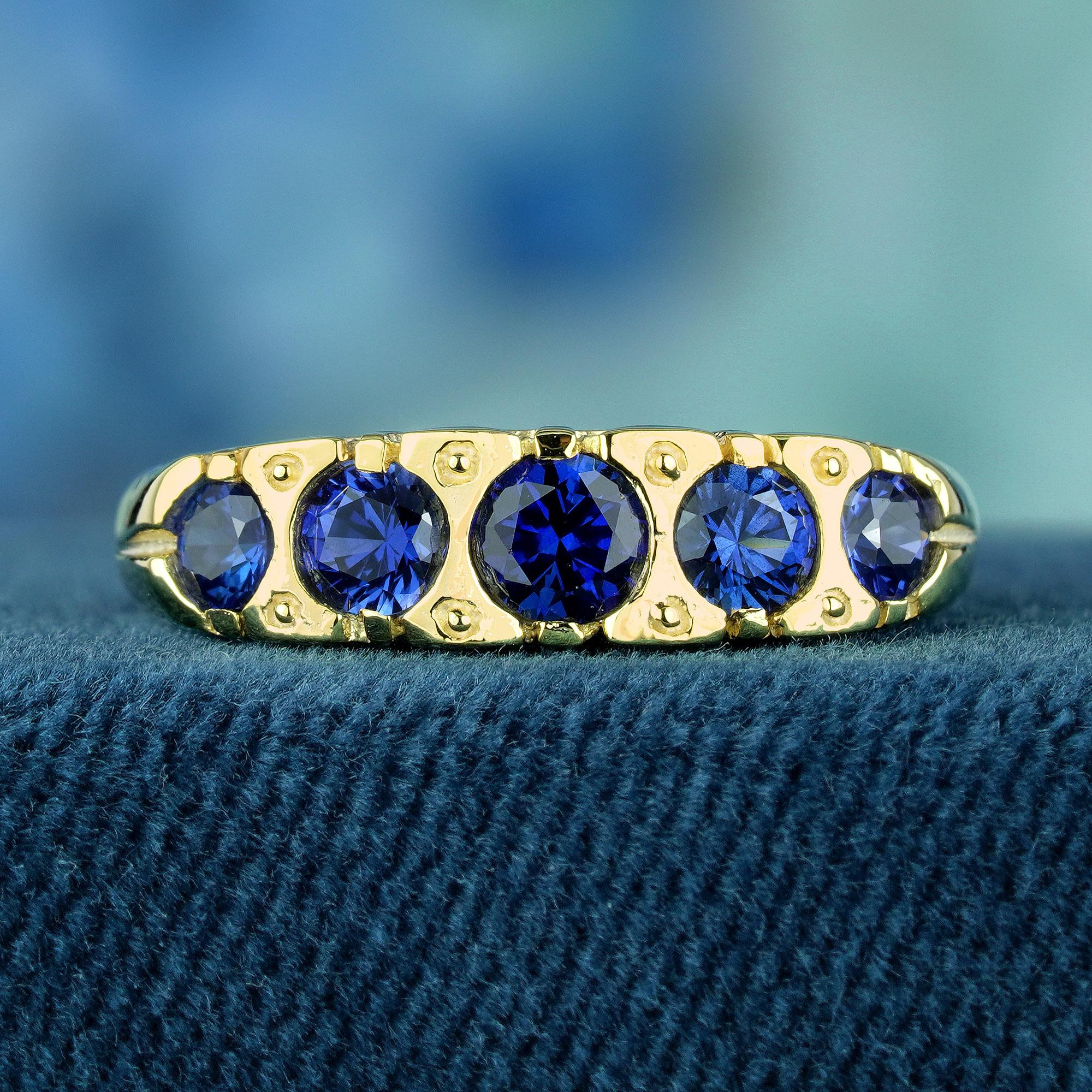 Dieser exquisite Ring im Vintage-Stil ist mit runden, natürlichen blauen Saphiren verziert, die auf einem glatten und glänzenden Gelbgoldband ruhen. Die zarte Fünf-Stein-Fassung des Rings versprüht einen Hauch von Vintage-Glamour, während das