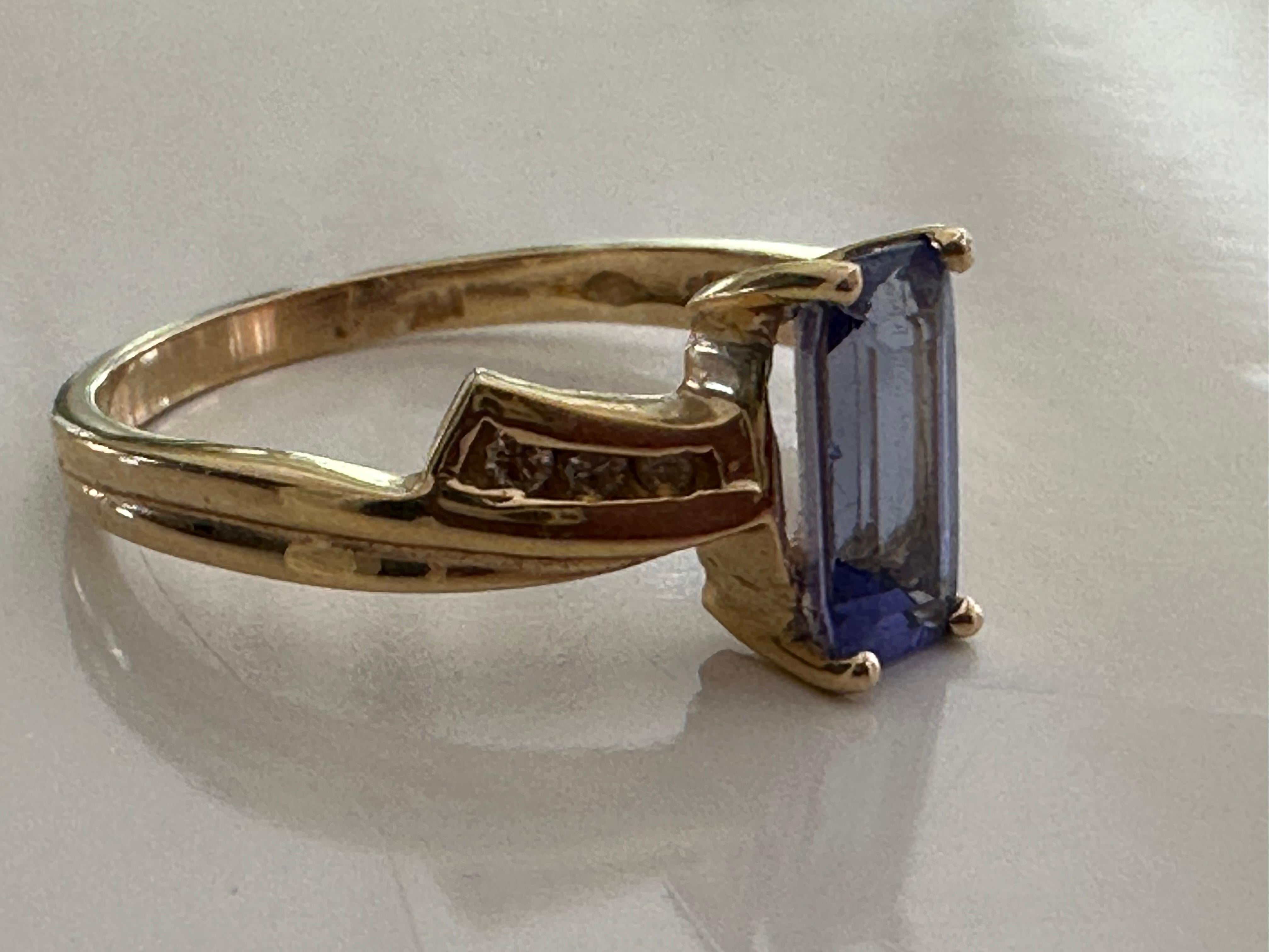 Crafted in the 1970s, this Retro-era ring is designed around a long cushion-cut natural blue tanzanite measuring approximately 1.28 carats flanked by six round diamonds, three on each side, measuring approximately 0.07 carats and fashioned in a 14kt