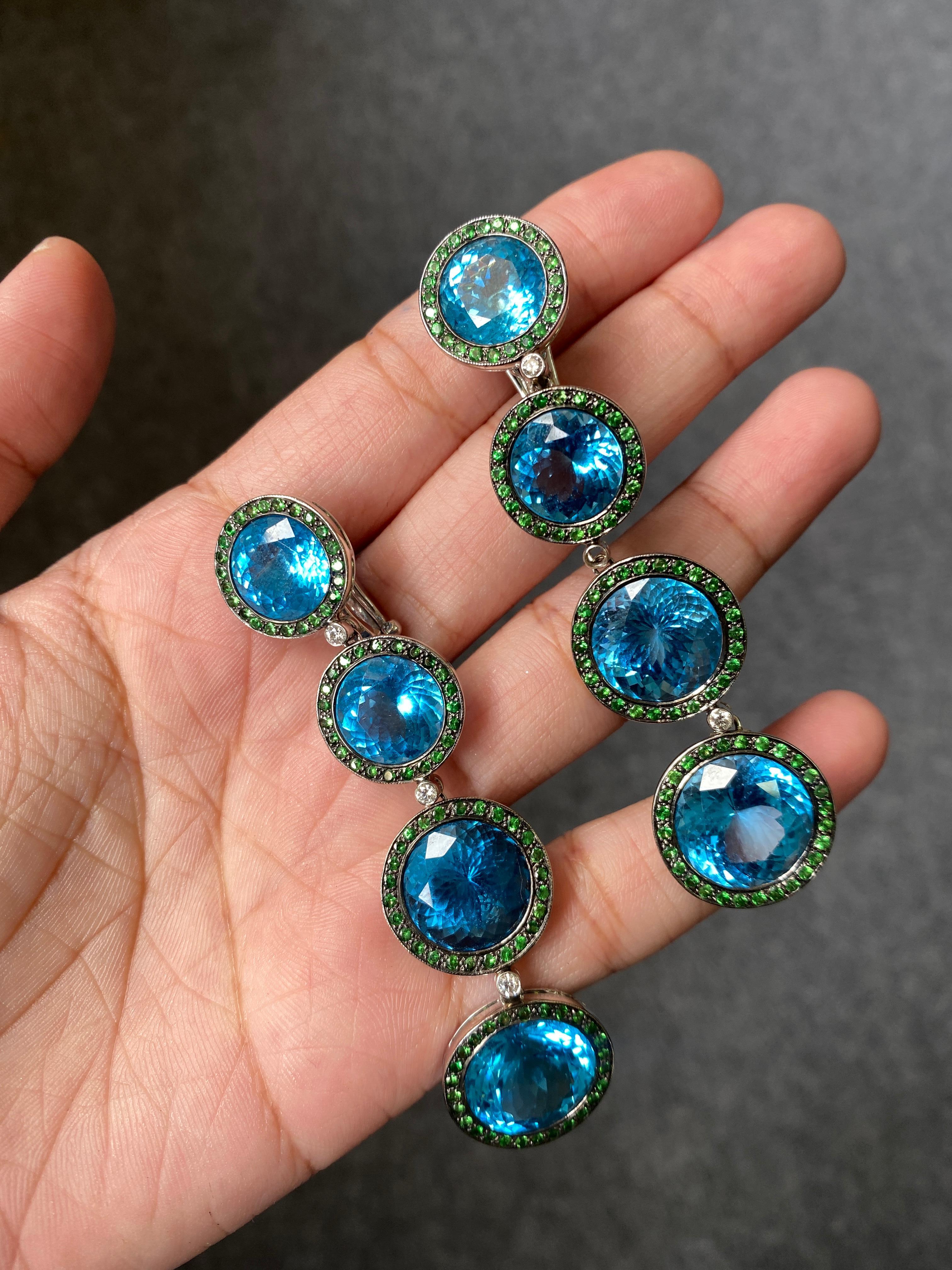 Make a statement when you wear this beautiful pair of Blue Topaz and Green Garnet earrings, set in 18K Gold. The length of the earrings are 3 inches long. 