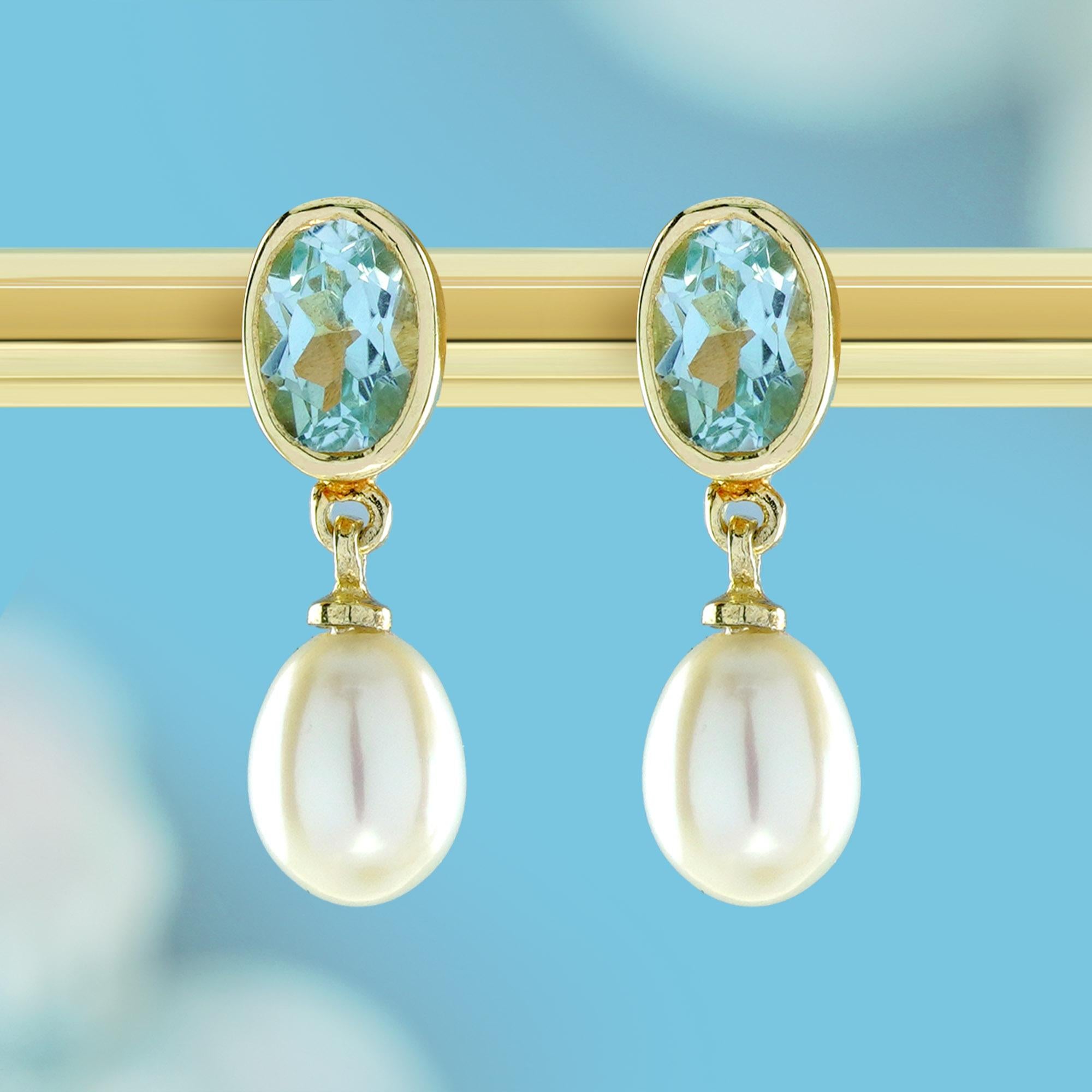 Entra in un'eleganza senza tempo con questi orecchini di ispirazione vintage, un'accattivante miscela di elementi classici e motivi naturali. Al centro di ogni orecchino si trova un topazio blu di forma ovale, incastonato in una montatura d'oro, che
