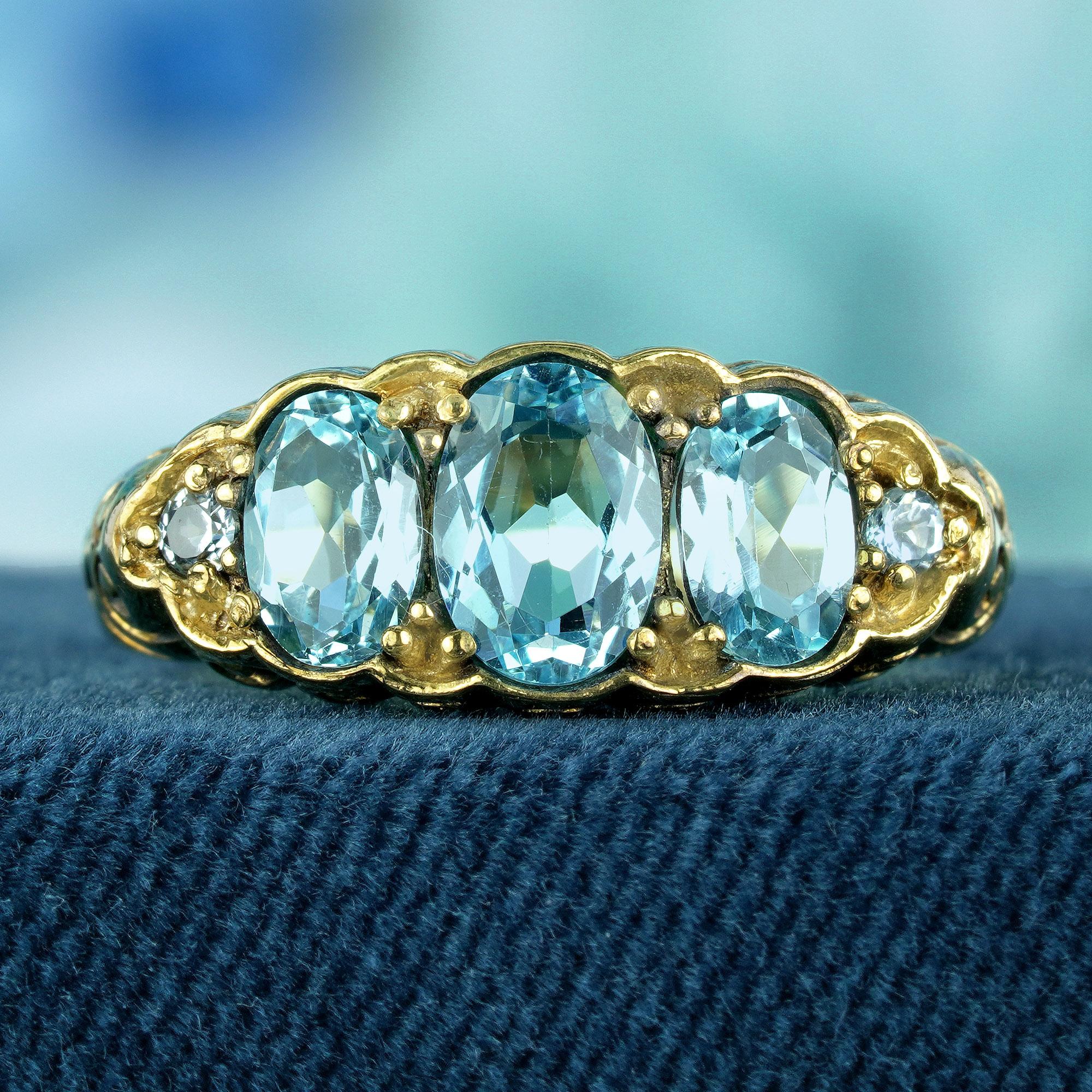 Abbraccia una raffinatezza senza tempo con il nostro anello a tre pietre intagliate in oro con topazio in stile vintage. Realizzato con dettagli intricati e impreziosito da tre affascinanti pietre di topazio blu, questo anello emana eleganza e
