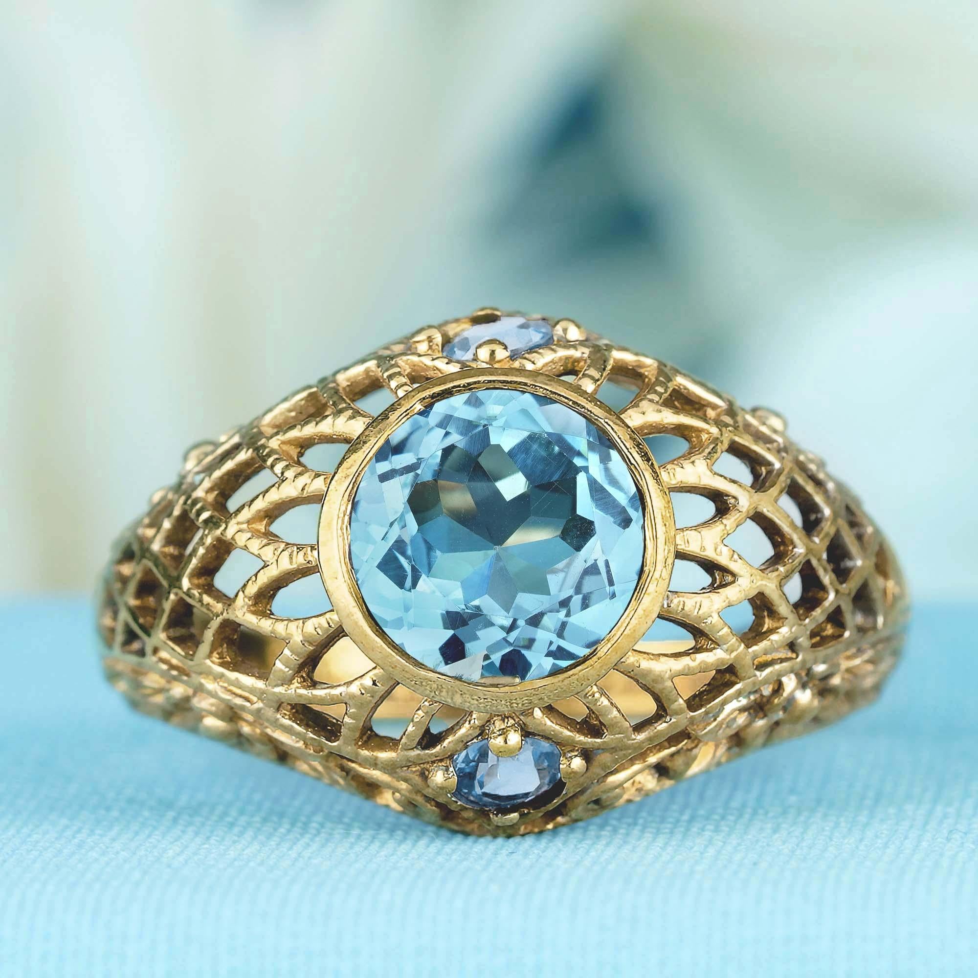 Cette bague d'une élégance intemporelle présente un style vintage classique avec un travail filigrané complexe en or jaune. Son design délicat respire la sophistication, ce qui en fait une pièce véritablement captivante. La topaze bleue ronde est