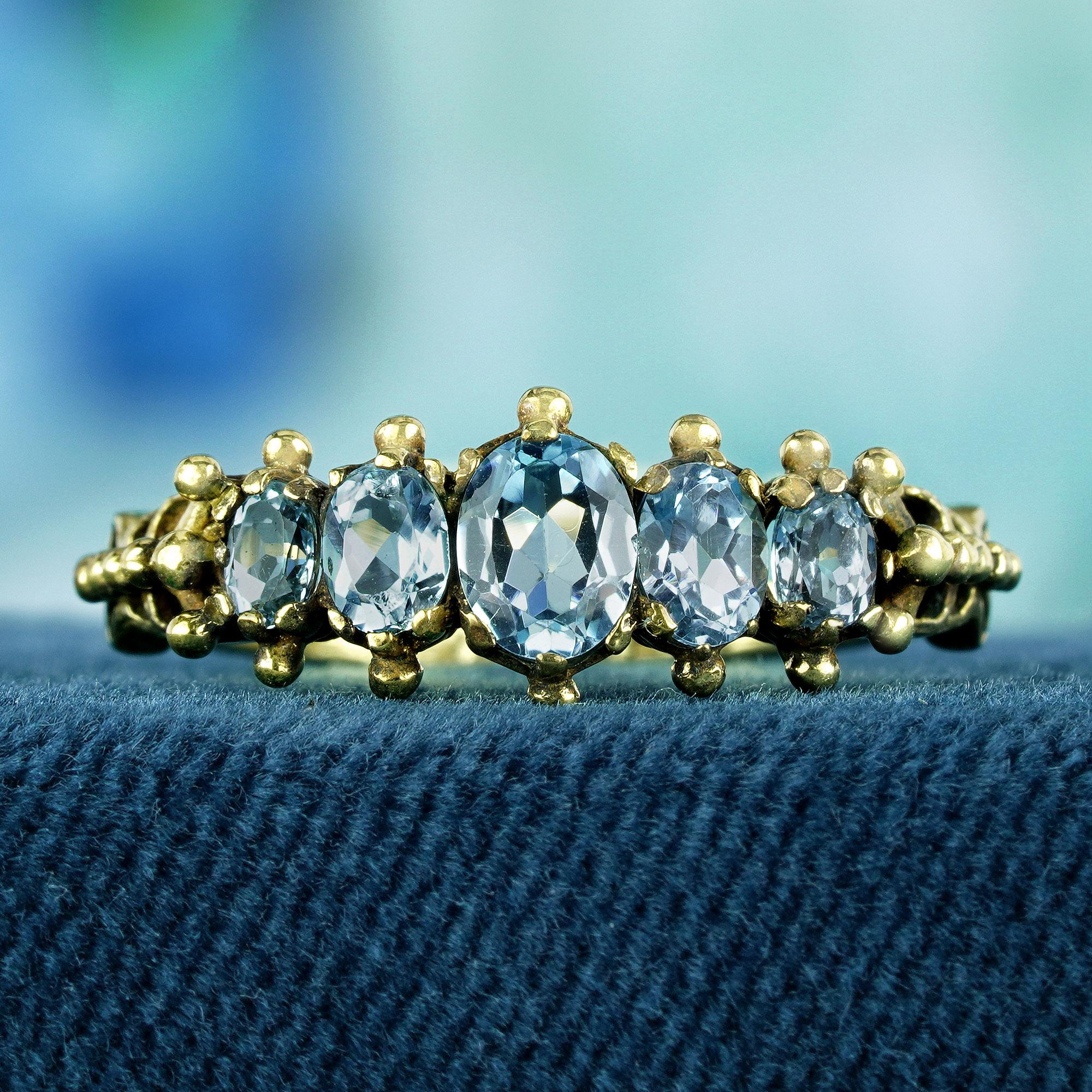 Entdecken Sie zeitlose Eleganz mit unserem Fünf-Steine-Ring aus Gelbgold mit blauem Topas im Vintage-Stil, der zart in einer Zackenfassung liegt. Jeder himmelblaue, ovale Topasstein wurde sorgfältig arrangiert, um die Essenz von Raffinesse und Anmut