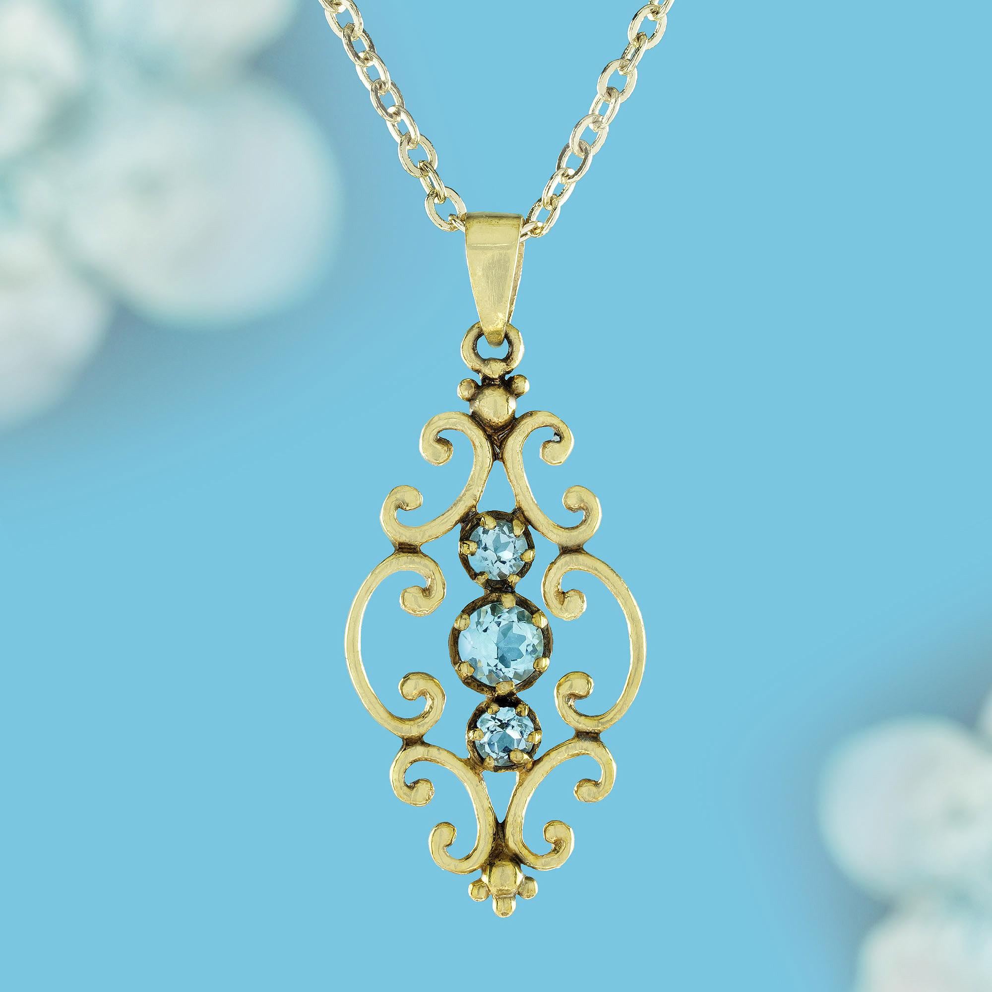 Unveil timeless elegance with our enchanting three-stone blue topaz pendant crafted in gleaming yellow gold. Each sky-blue topaz gemstone, a captivating round cut, is embraced by a delicate filigree design. This exquisite pendant whispers of a