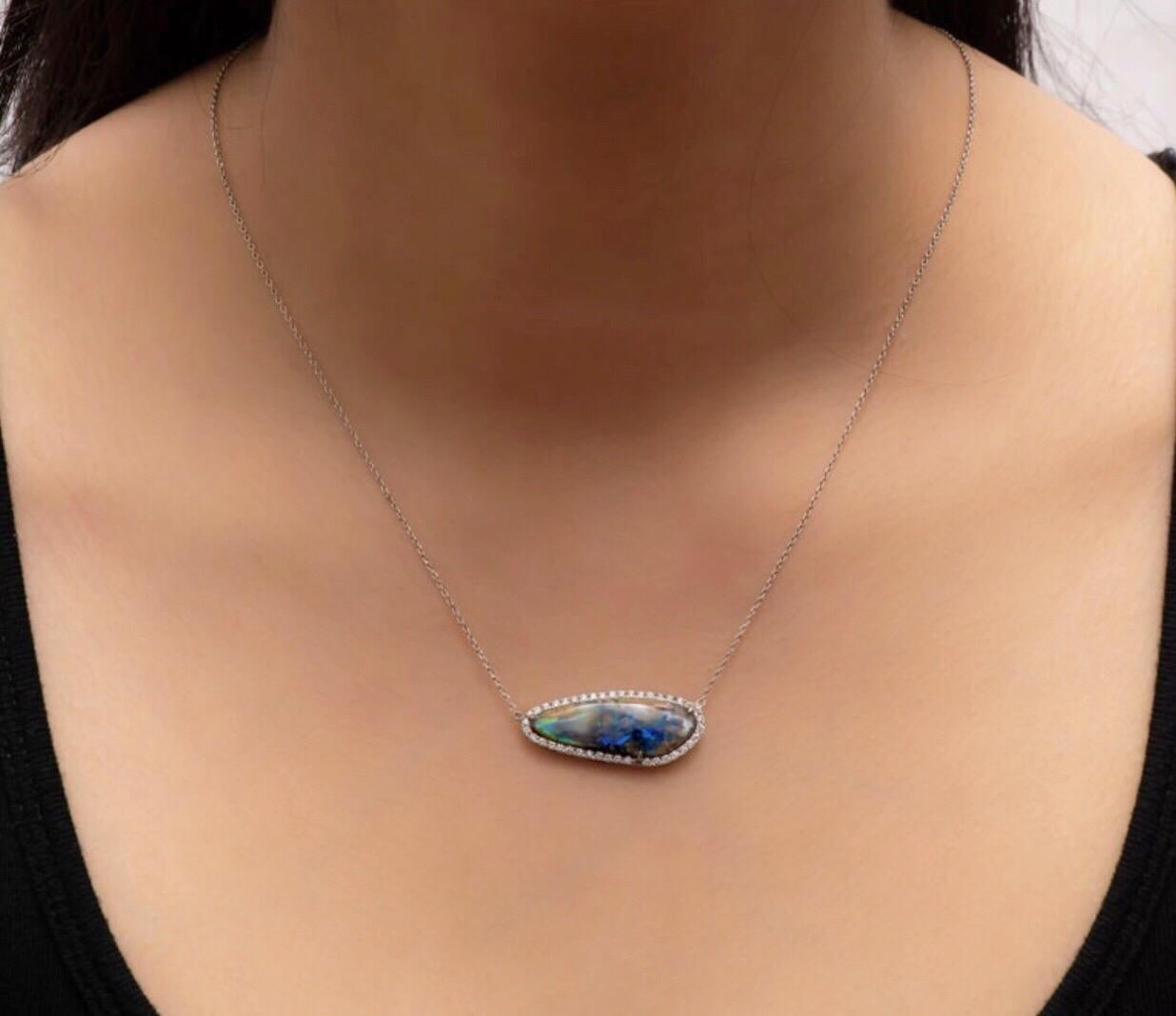 Natural boulder opal set in a halo of 0.42 carats total in fine round brilliant cut diamonds set in a 14K white gold pendant that is attached to a 18