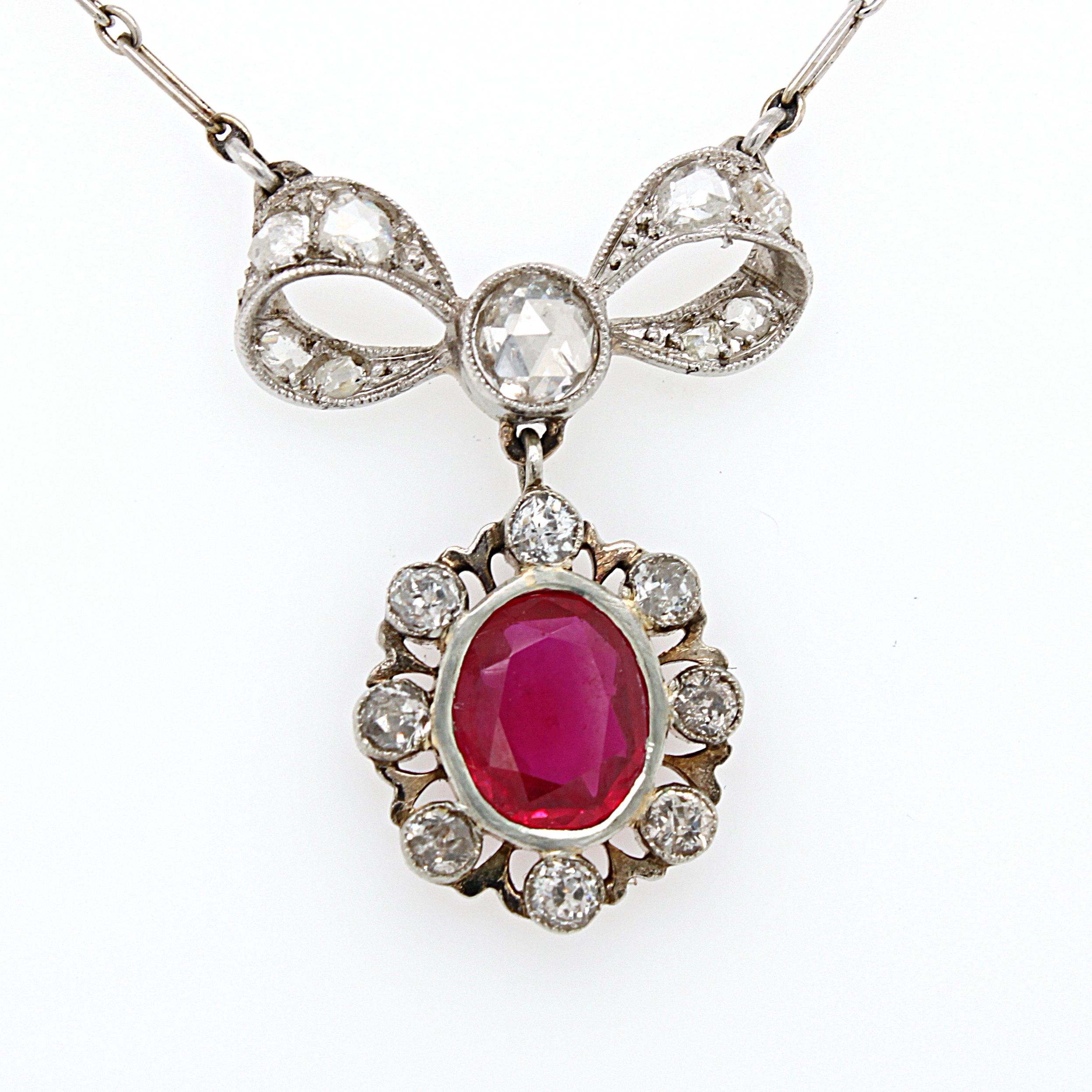 A lovely Belle Époque ruby and diamond bow necklace, ca. 1910s. The pendant is attached to a white gold chain, with the top part set with rose cut diamonds in a bow shape. The lower part is set with a beautiful ruby, which surrounded by round old