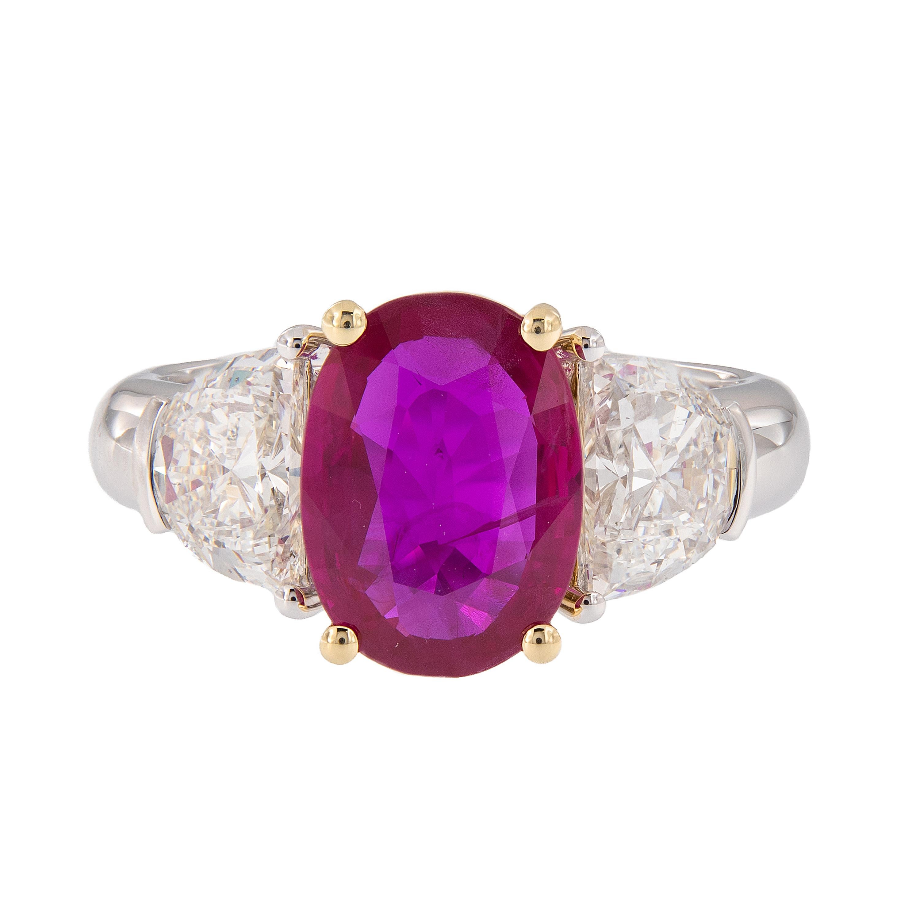 Make a statement with this beautiful and impressive three-stone ring. The ring centers around a stunning three carat oval cut natural Burma ruby accented with two moon-cut diamonds. The ruby is prong set and framed by 18k yellow gold and diamonds