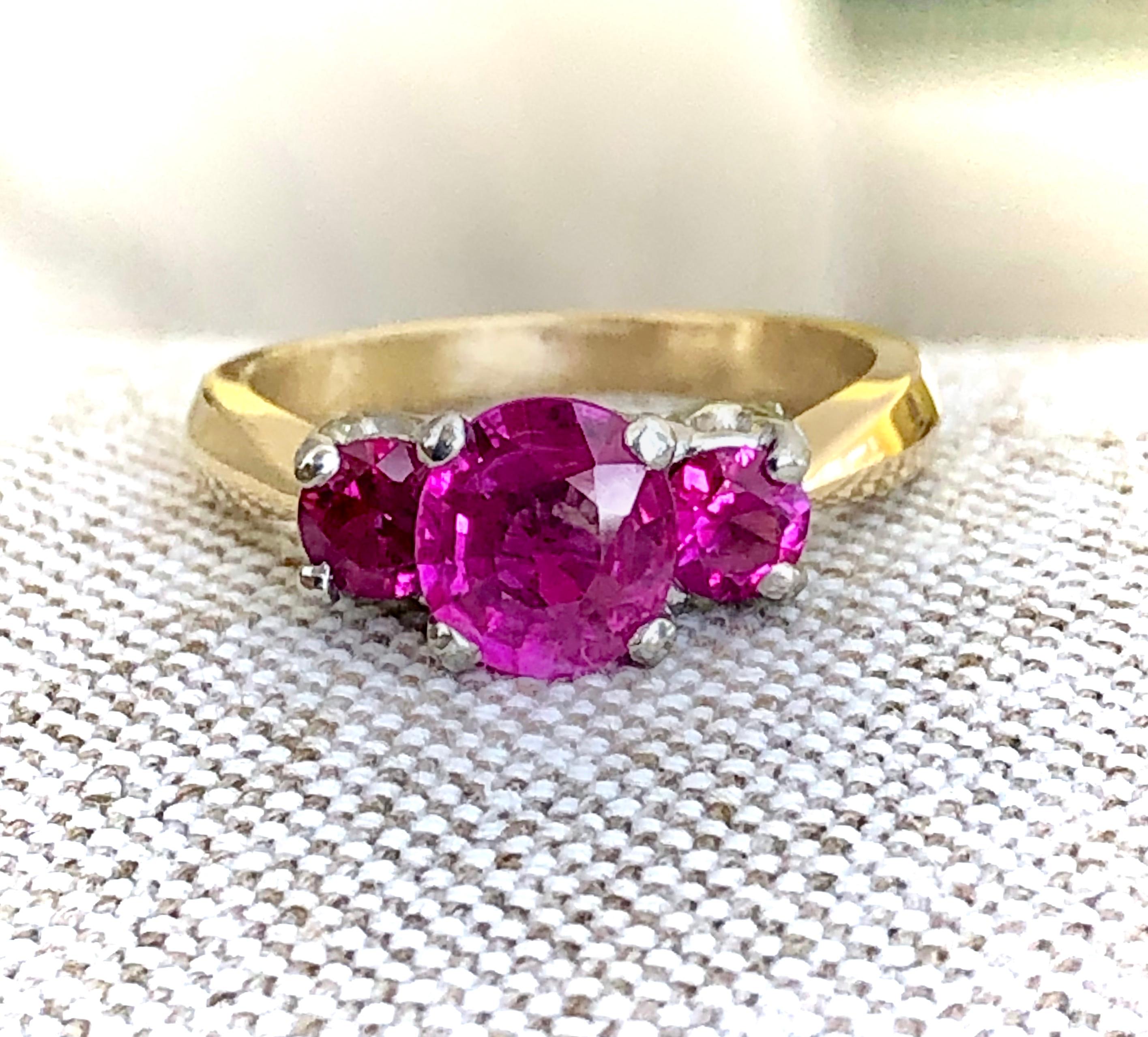 An estate vibrant pinkish red semi-oval-cut natural Burmese ruby, weighing 1.36 carats, between a sparkling pair of two Burmese rubies, together weighing 0.75 carats, set in a very classic three-stone platinum and 18K yellow gold mounting. The