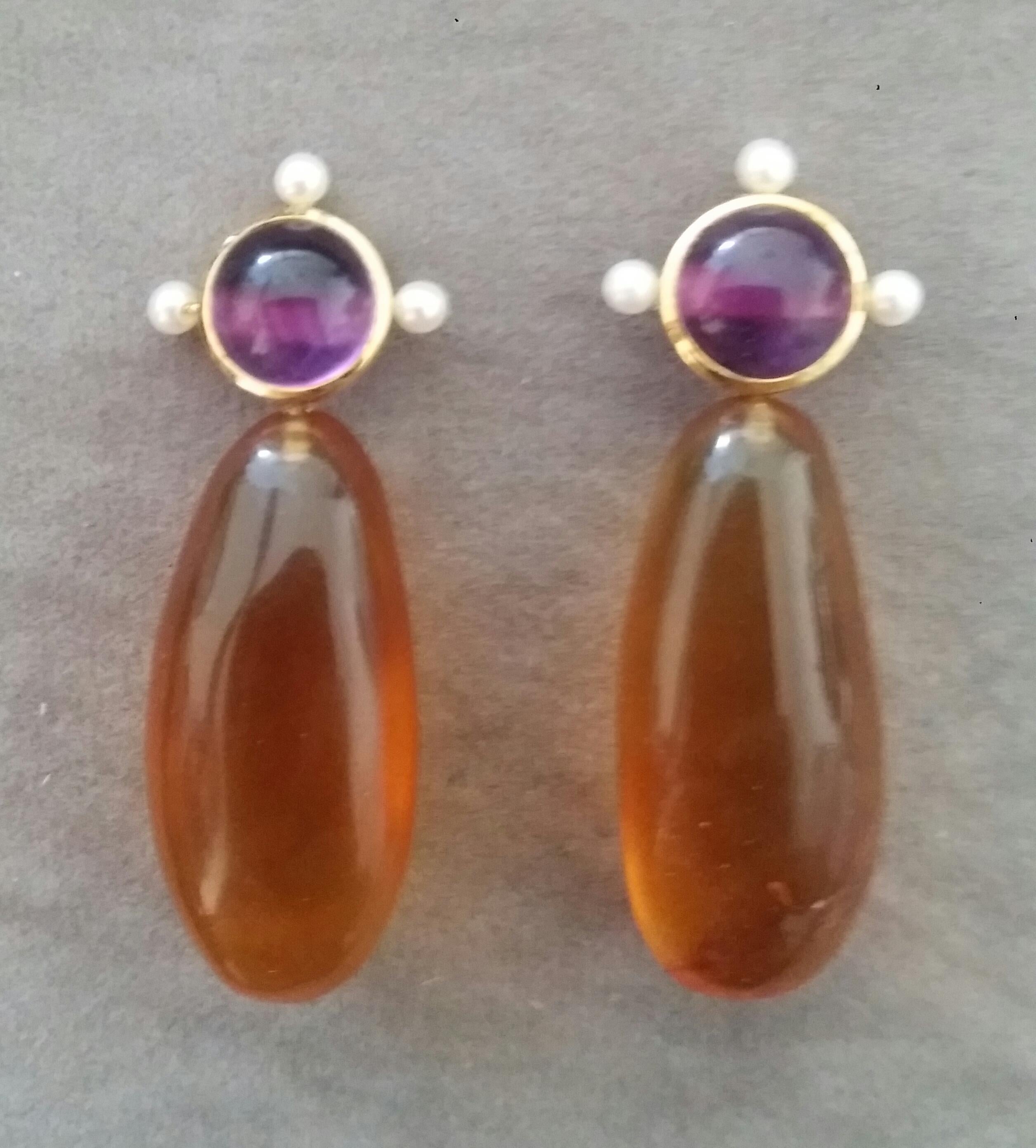 Dans cette paire de boucles d'oreilles 2 boutons ronds d'améthyste diamètre 10mm. supportent 2 gouttes d'ambre naturel de Birmanie (non chauffé) couleur miel de taille 16 x 36 mm.

En 1978, notre atelier a démarré en Italie pour fabriquer des bijoux