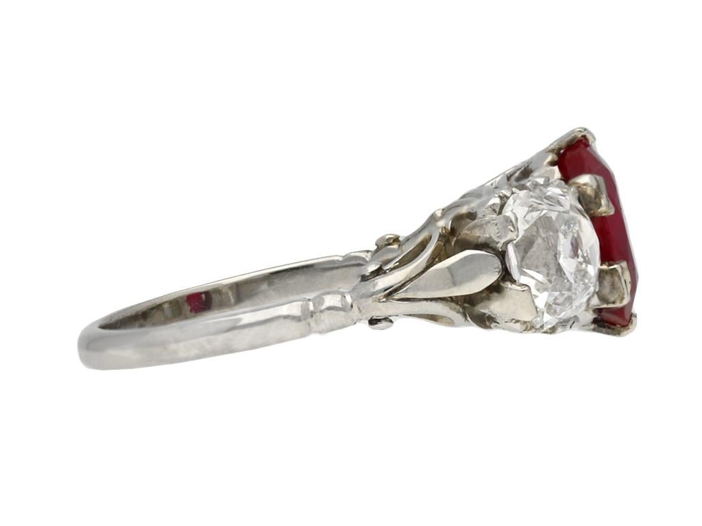 Anillo birmano de rubíes y diamantes con tres piedras. Engarzado en el centro con un rubí birmano natural sin realzar, talla antigua, en forma de cojín, en garra abierta por detrás, con un peso de 1,94 quilates, engastado además con dos diamantes