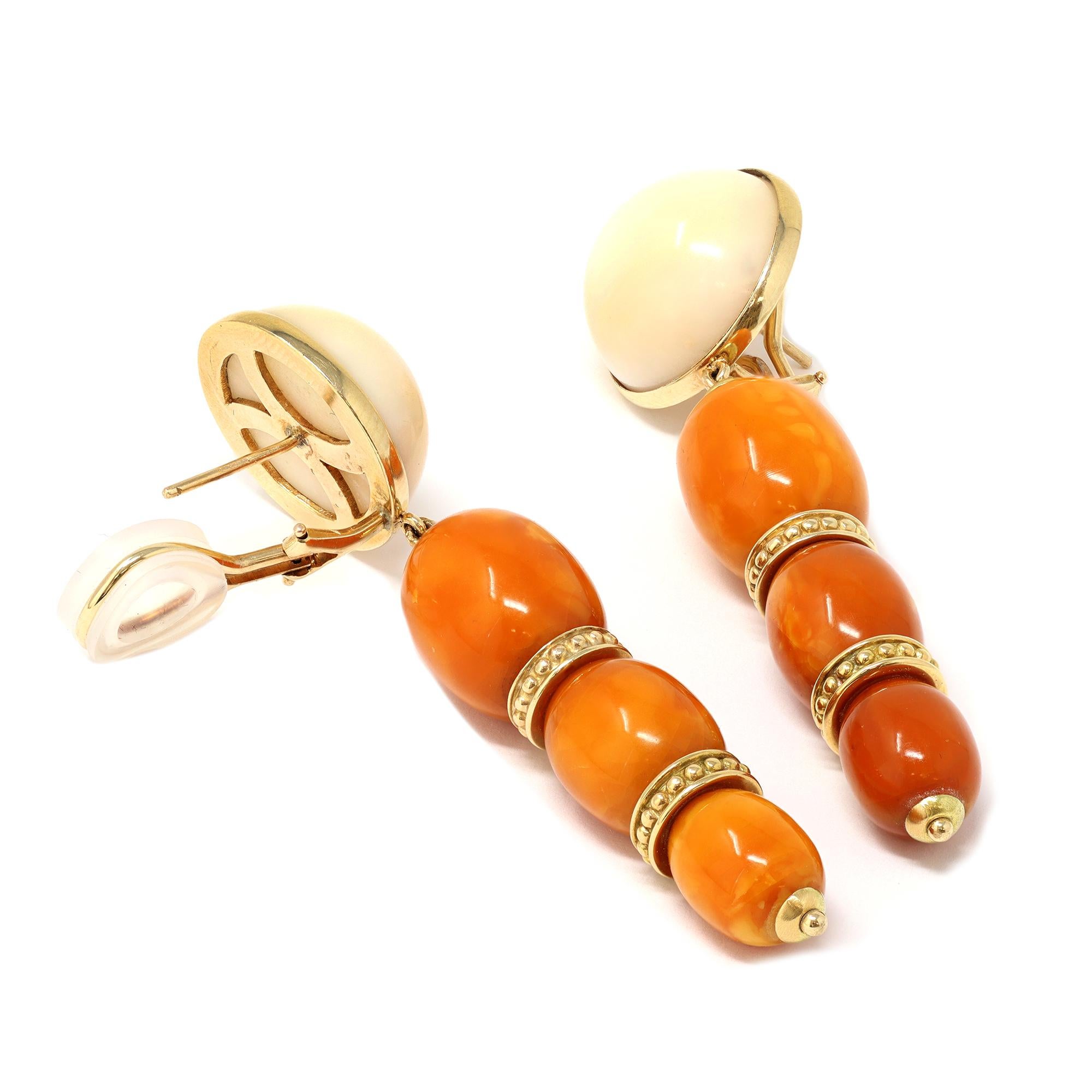 A unique pair of dangling earrings circa 1960-70 featuring natural untreated “butterscotch” Amber bead pendants and White coral cabochon studs. The earrings are set in 14 karat yellow gold. 
These vintage earrings are in pristine condition.  The