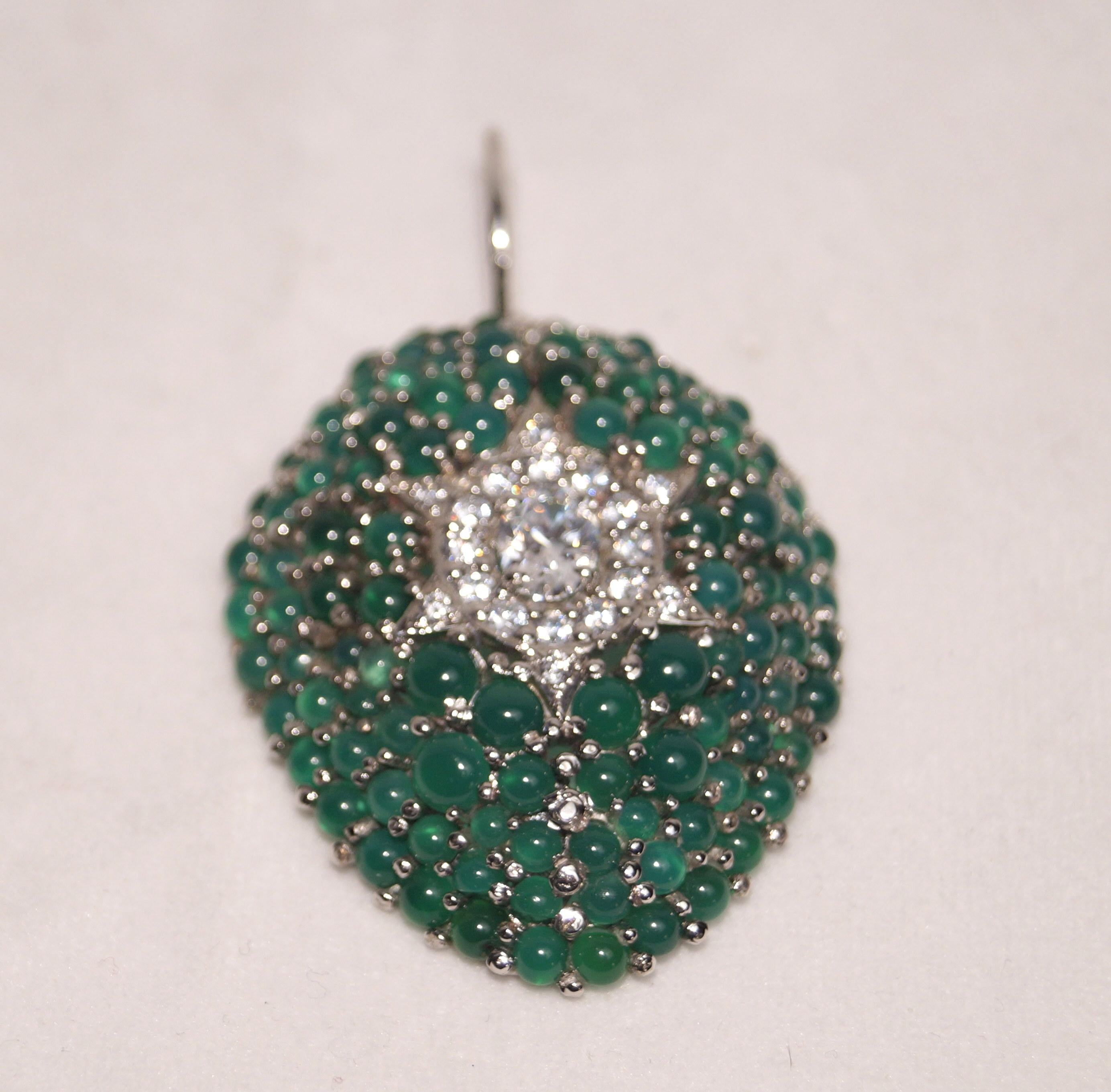 Lassen Sie sich von der zeitlosen Anziehungskraft unseres exquisiten ovalen Anhängers verzaubern, der mit einer Reihe von Cabochon-Smaragden und einem funkelnden Diamantstern in der Mitte geschmückt ist. Dieser mit Präzision und Sorgfalt gefertigte