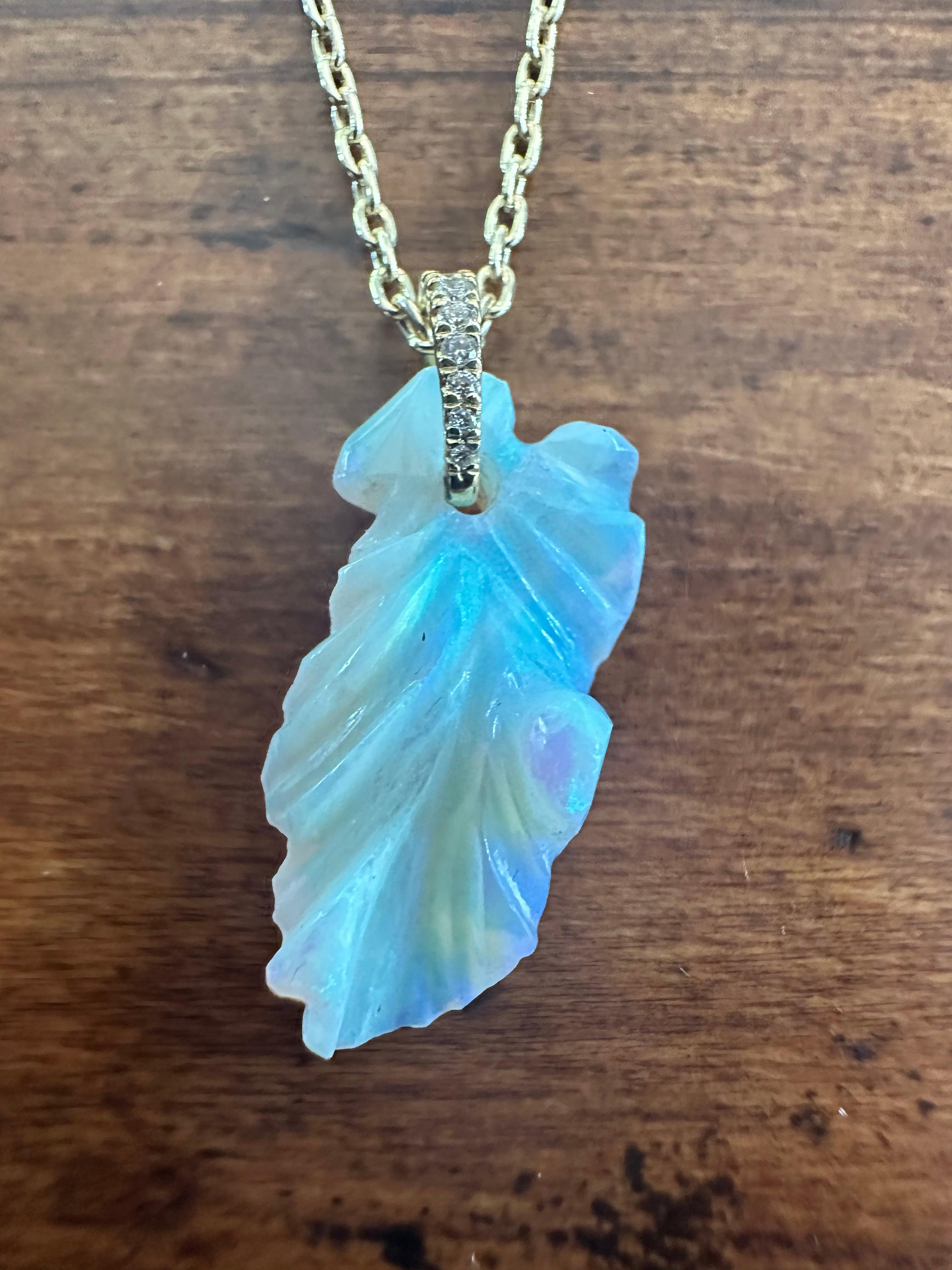Handcrafted in 18K yellow gold, this beautiful leaf pendant necklace features a 6.57-carat natural fine green-blue tinted carved opal accented with eight round diamonds totaling 0.10 carats. The necklace measures 18 inches. 
