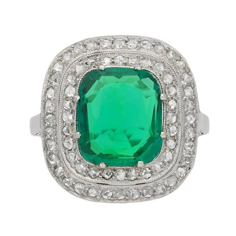 No Oil Emerald and diamond cluster ring. Set with a central cushion shape old cut natural Colombian emerald with no colour enhancement and no clarity enhancement in an open back claw setting with an approximate weight of 2.11 carats, encircled by