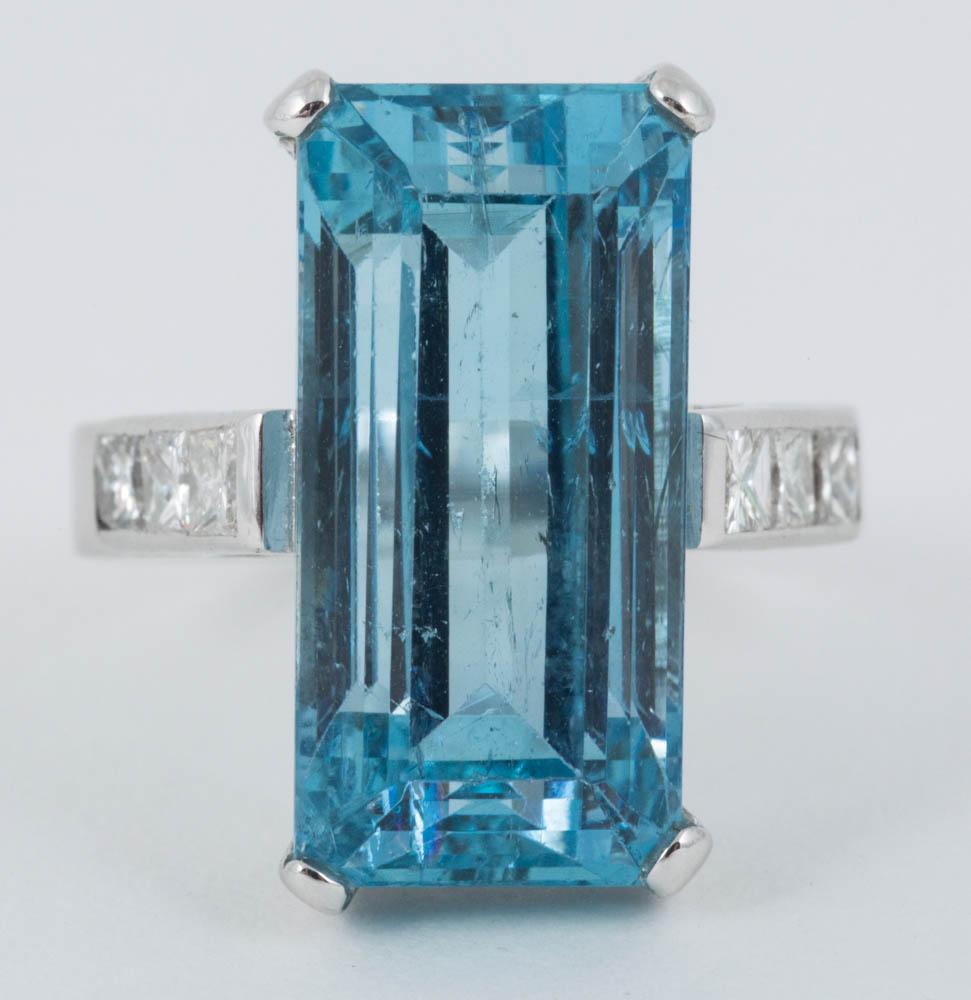 size A Natural coloured Aquamarine ring of Emerald cut measuring 18mm in length and 9mm wide mounted in 18ct white gold,with three,square cut diamonds in each shoulder c,1980 size N and a half