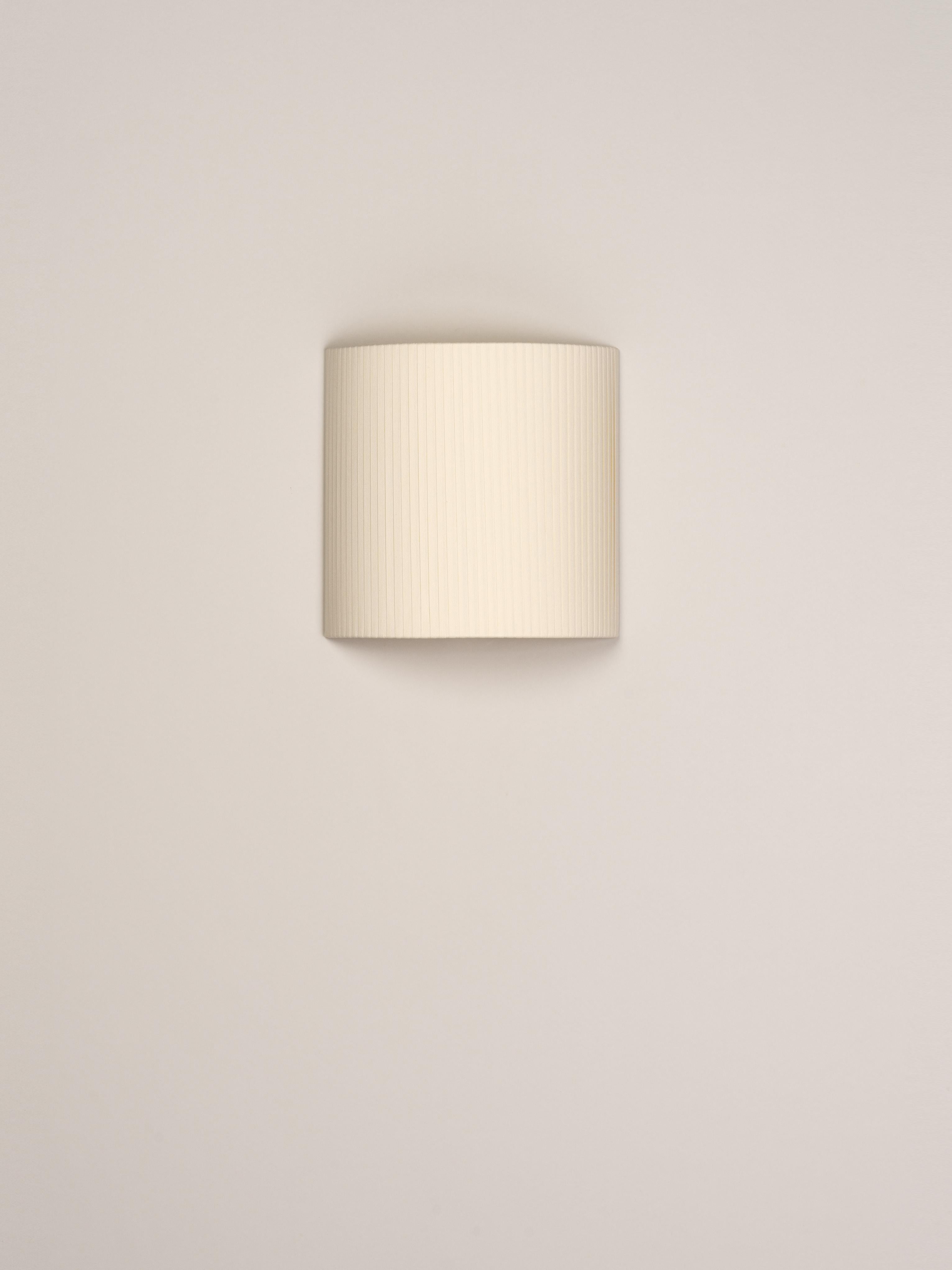 Natural comodín cuadrado wall lamp by Santa & Cole
Dimensions: D 31 x W 13 x H 30 cm
Materials: Metal, ribbon.

This minimalist wall lamp humanises neutral spaces with its colourful and functional sobriety. The shade is fondly hand-ribboned,