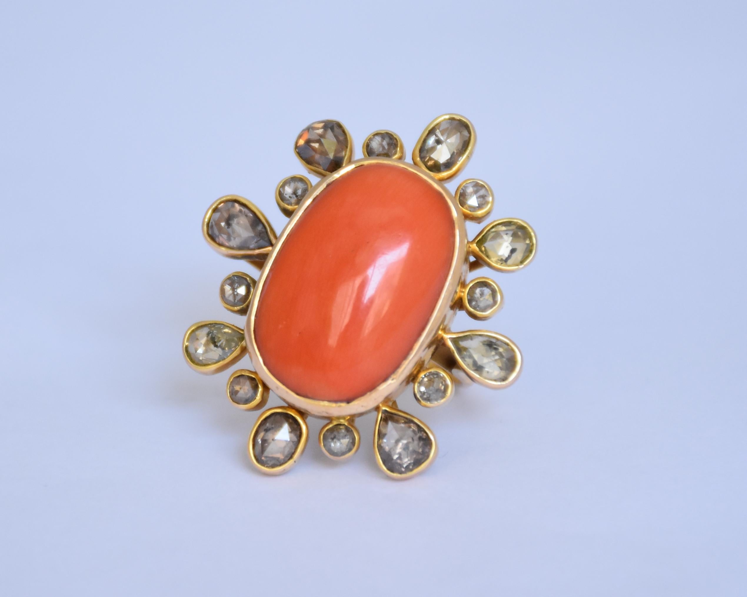A natural 23.15ct oval shaped italian coral set along with fancy colour rose cut diamonds in 14K gold. The coral set is completely clean and have no inclusions. The centre piece is open from the back to admire the beauty of the stone. 