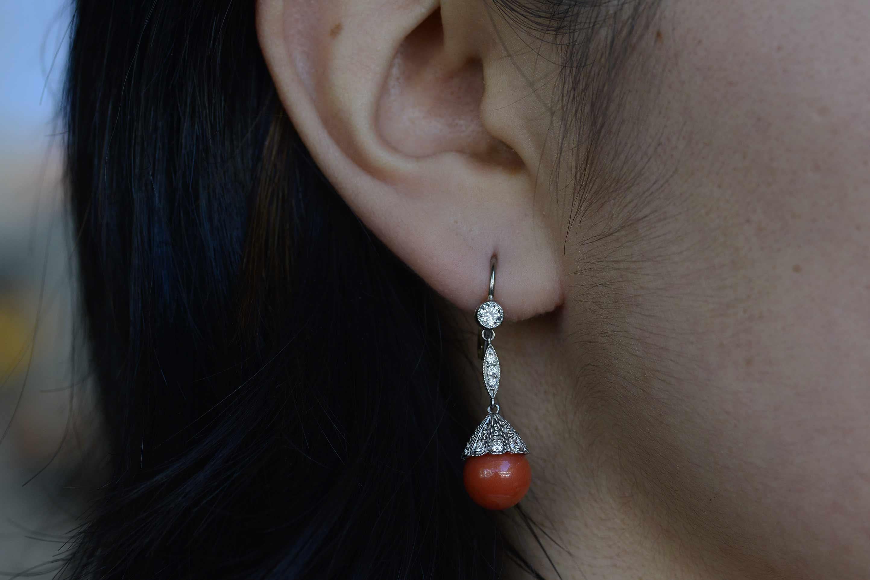 The Missoula Antique Earrings. The seductive red of these Art Deco Coral dangle earrings are sure to capture admiring glances as they sway so lithely with a long drop. The sizable 10mm spheres, topped with a pagoda like platinum and pave' diamond
