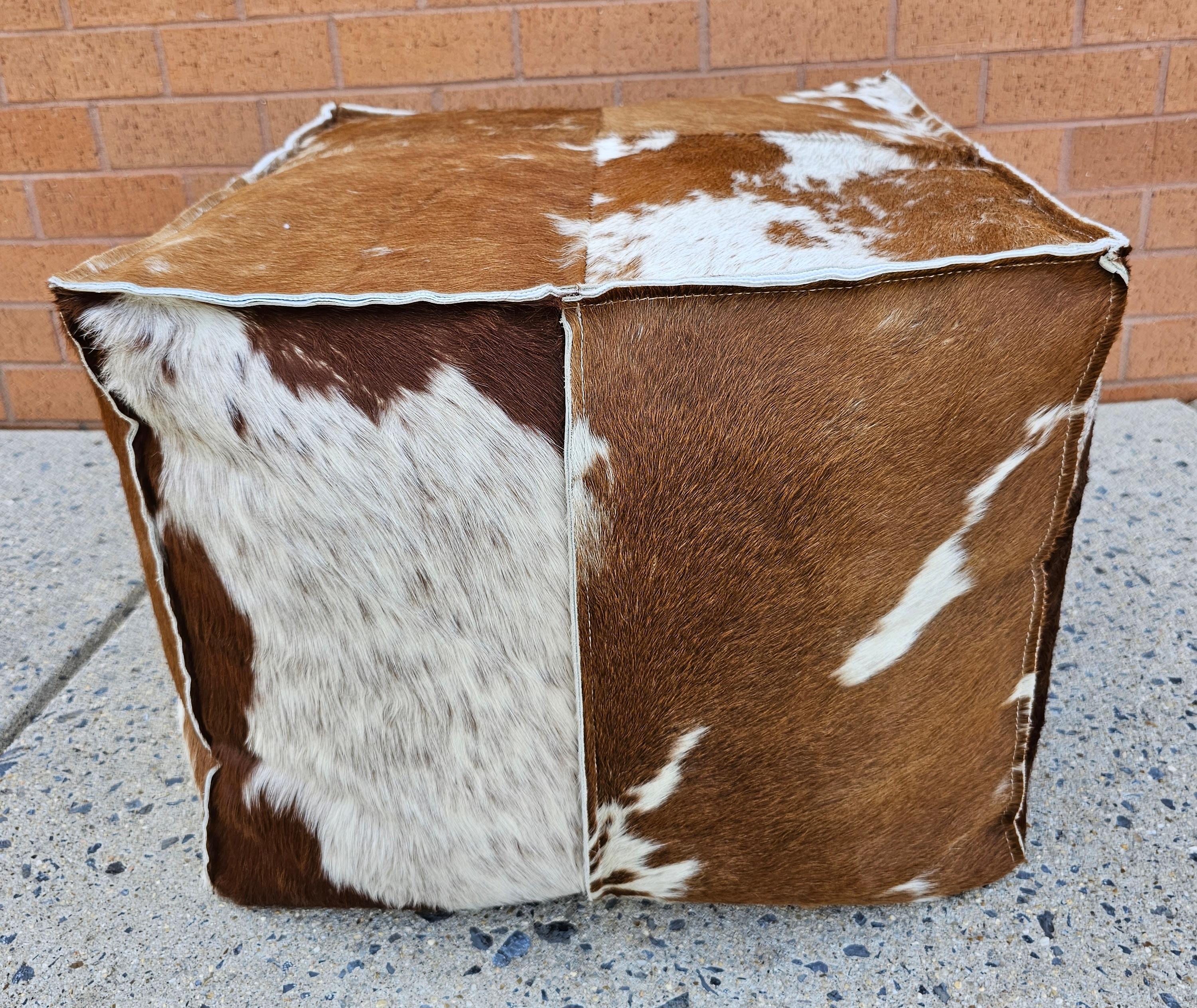 Cowhide cube ottoman with leather stitched detail around the edges for additional strength. This cowhide ottoman is unique and natural product. Measures 20