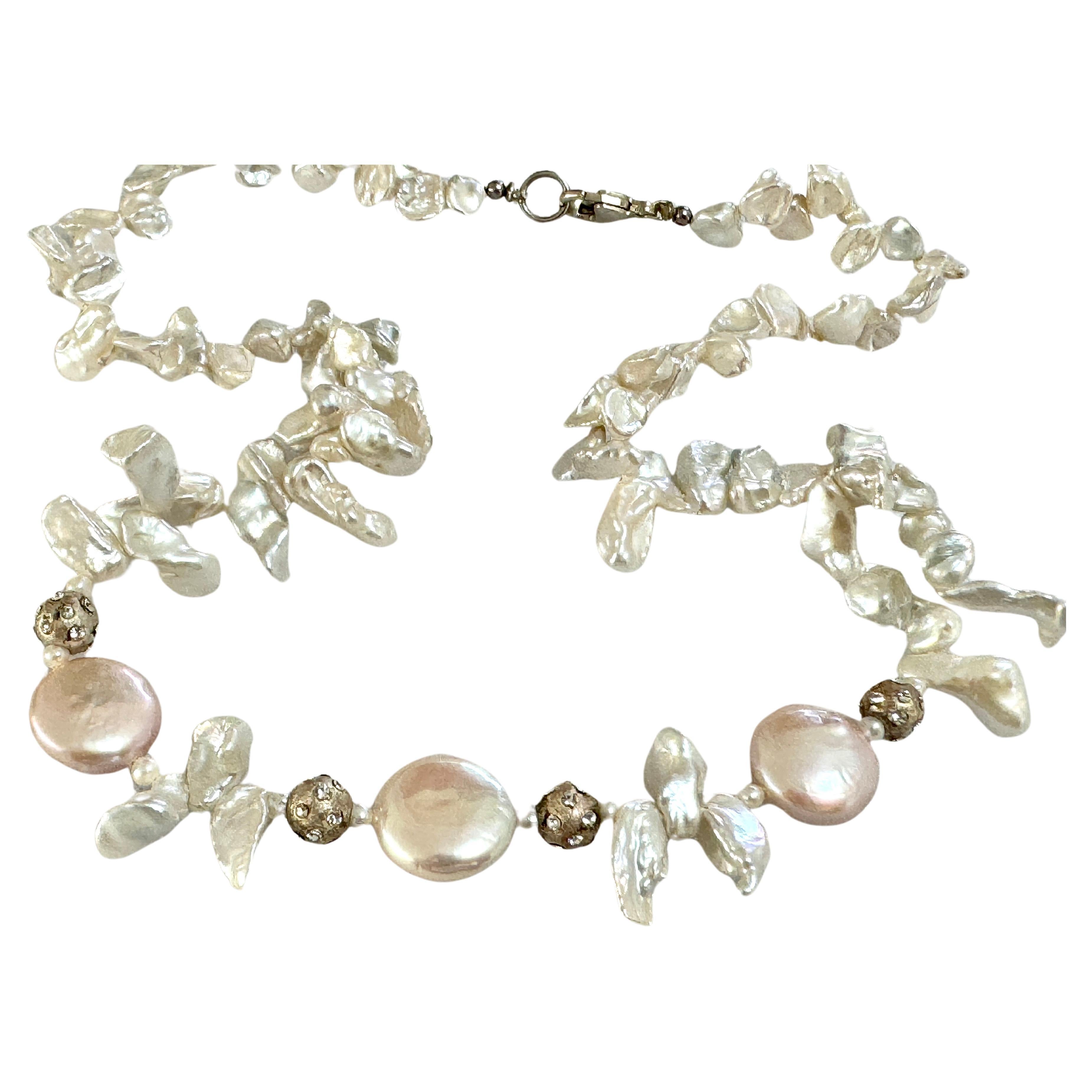 Collana di perle Keshi e monete d'acqua dolce
Perle keshi graduate bianche e lucenti, uniche nel loro genere, arricchite da perle rosa, perle rotonde in argento sterling e strass.  Chiusura in argento 925 lunga circa 17