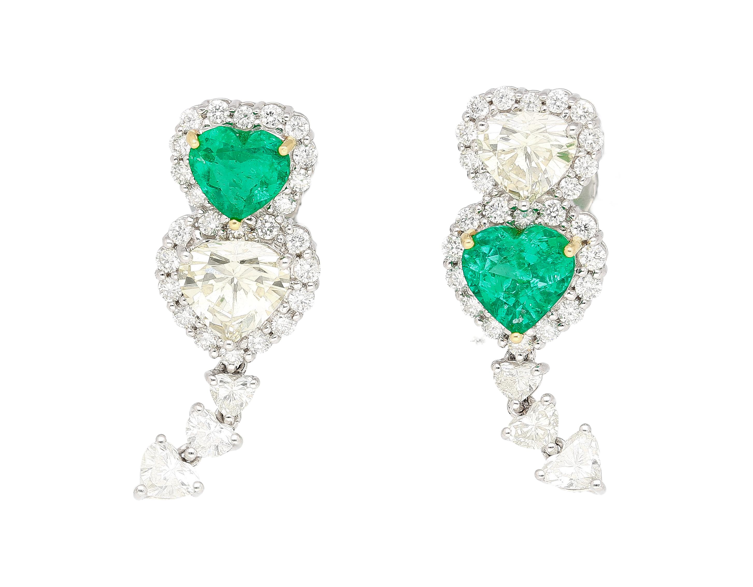 A dazzling mirrored opposite heart motif natural diamond and emerald drop earrings. Set with 1.95 carats in heart-cut emeralds and 3.23 carats in heart-cut diamonds. Handmade with intention and attention to detail. Precisely the color contrast of