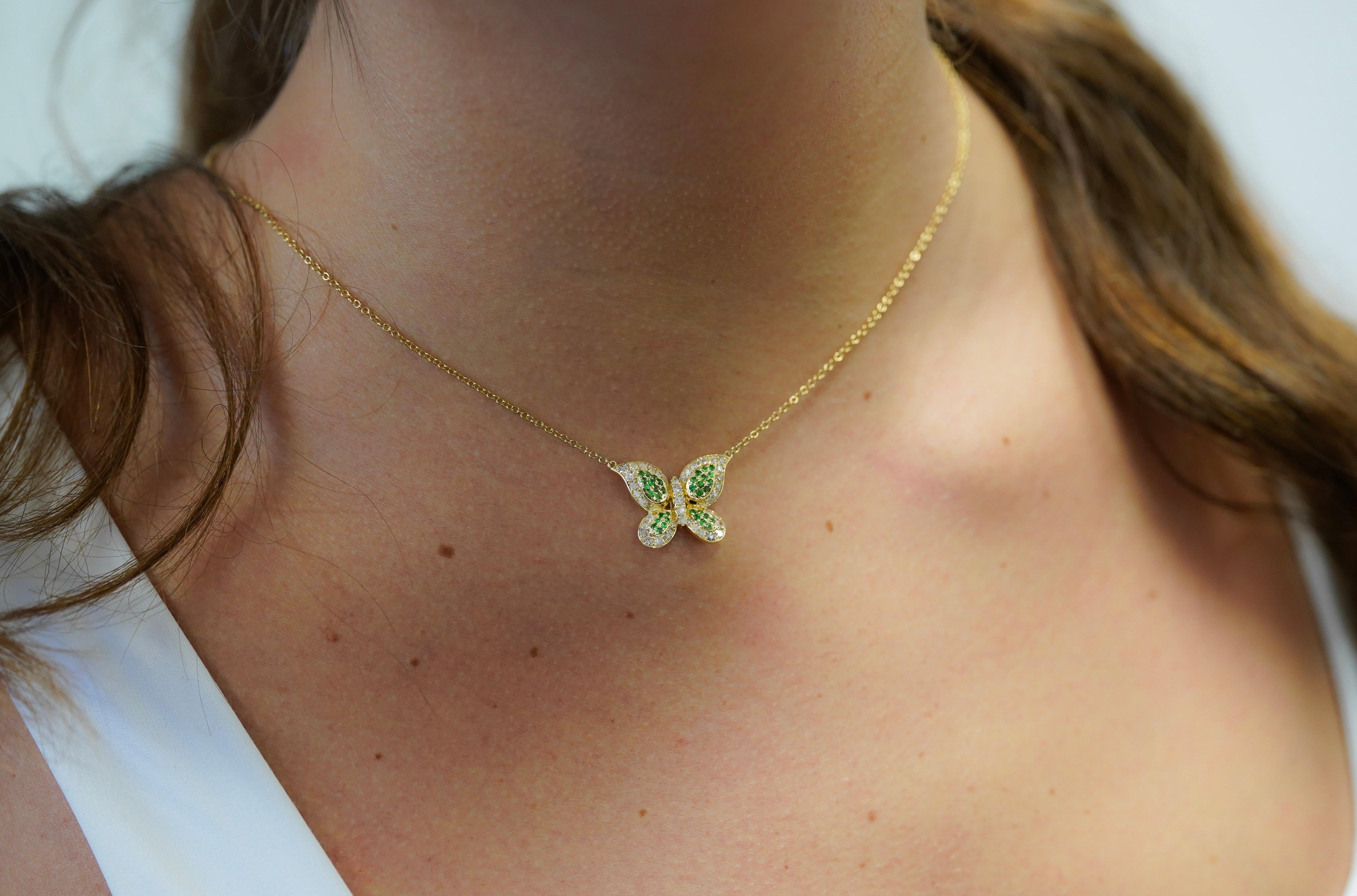 Nous vous présentons notre superbe collier pendentif à motif papillon en tsavorite verte naturelle et diamant, délicatement enveloppé dans l'éclat radieux de l'or jaune 14 carats.

Ce pendentif met en valeur de vibrantes ailes de tsavorite verte de