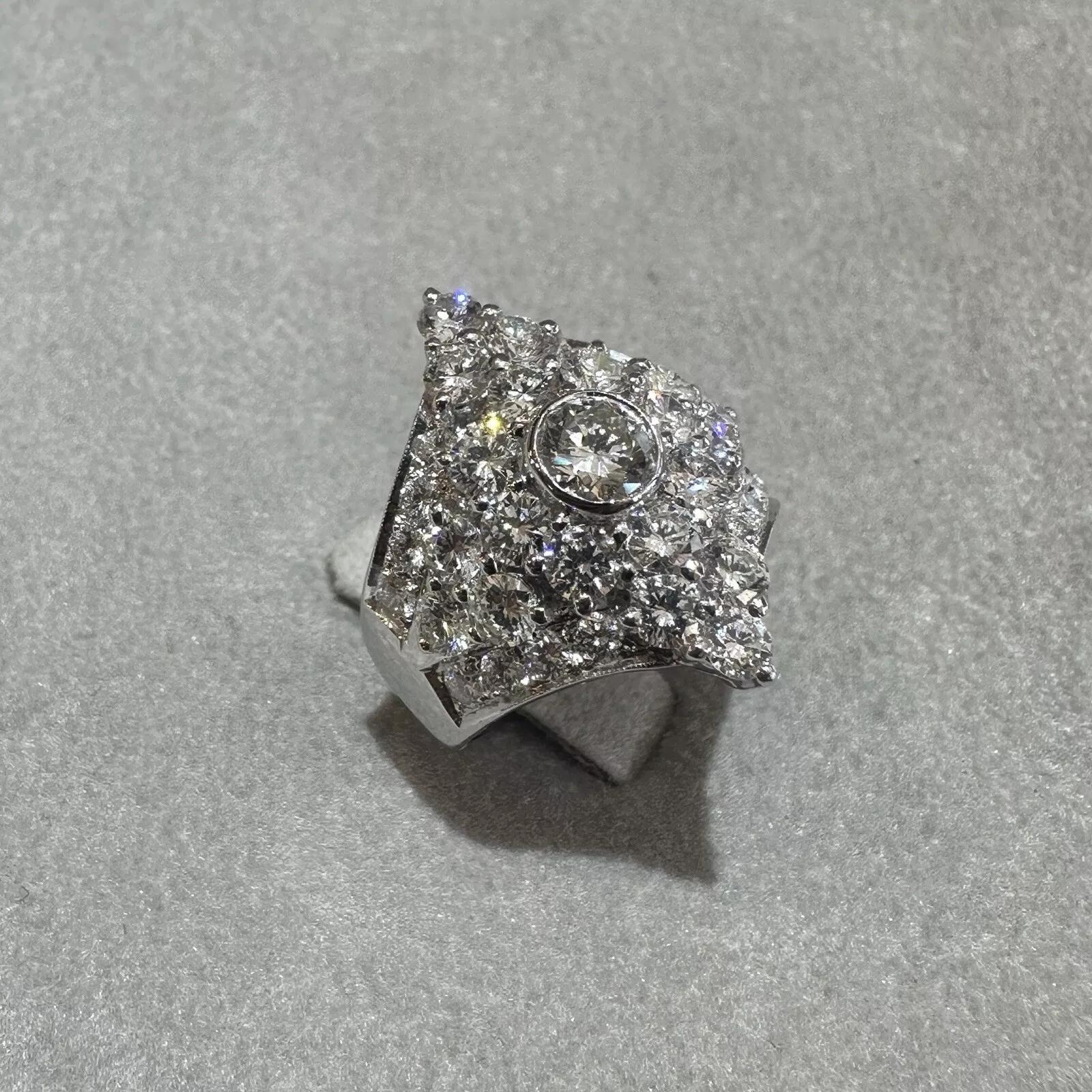 Anillo de Cóctel de Diamantes Naturales de 2,03 quilates de peso total en Platino 

El Anillo Ancho de Diamantes tiene un Diamante Redondo engastado en bisel en el centro, rodeado de Diamantes Brillantes Redondos engastados en Platino. 

El peso