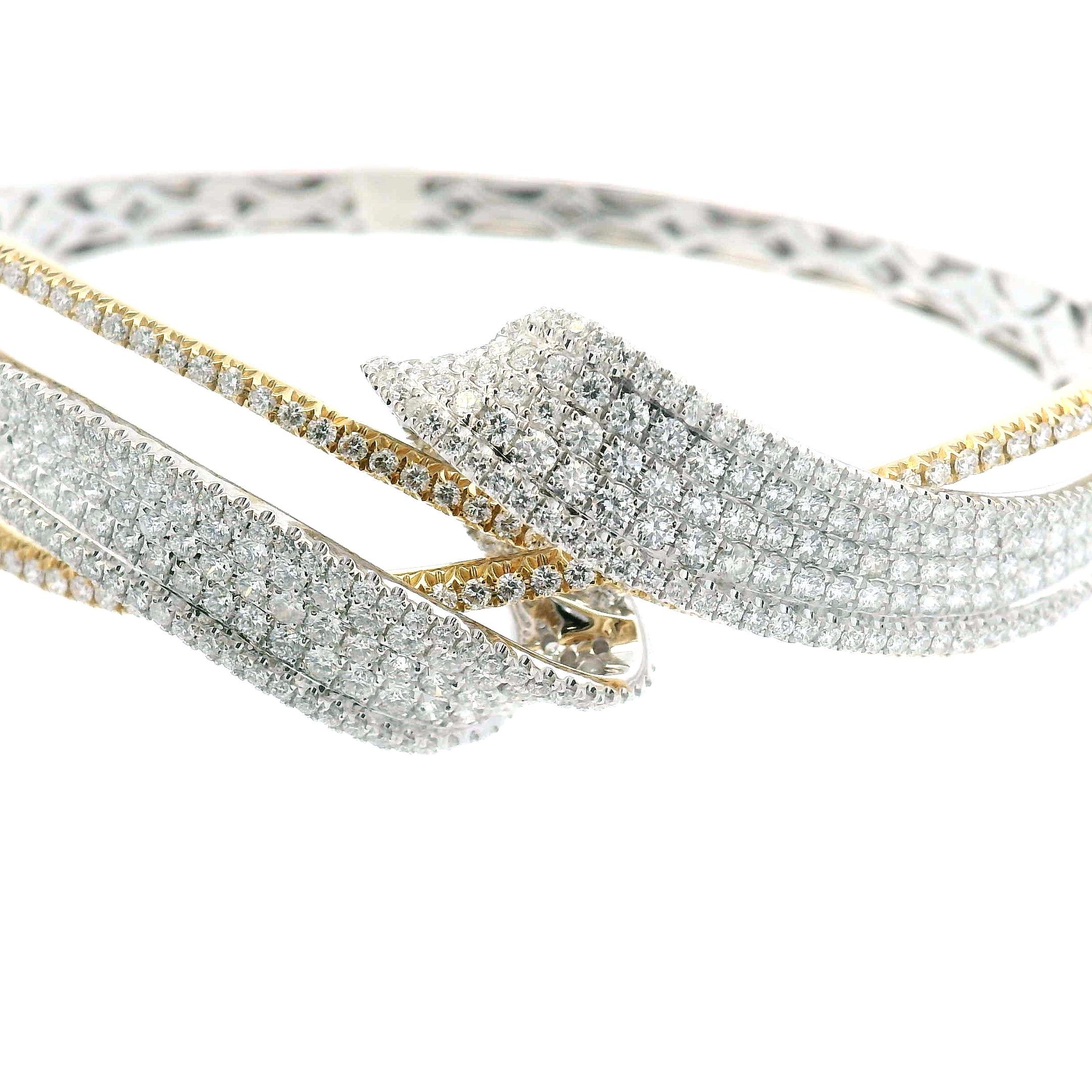 This two-tone diamond bangle blends bold structure with refined detailing. Crafted in 14K yellow and white gold, the crossover design is set with 4.25 carats of natural round brilliant-cut diamonds. With over 450 stones, the surface shimmers from