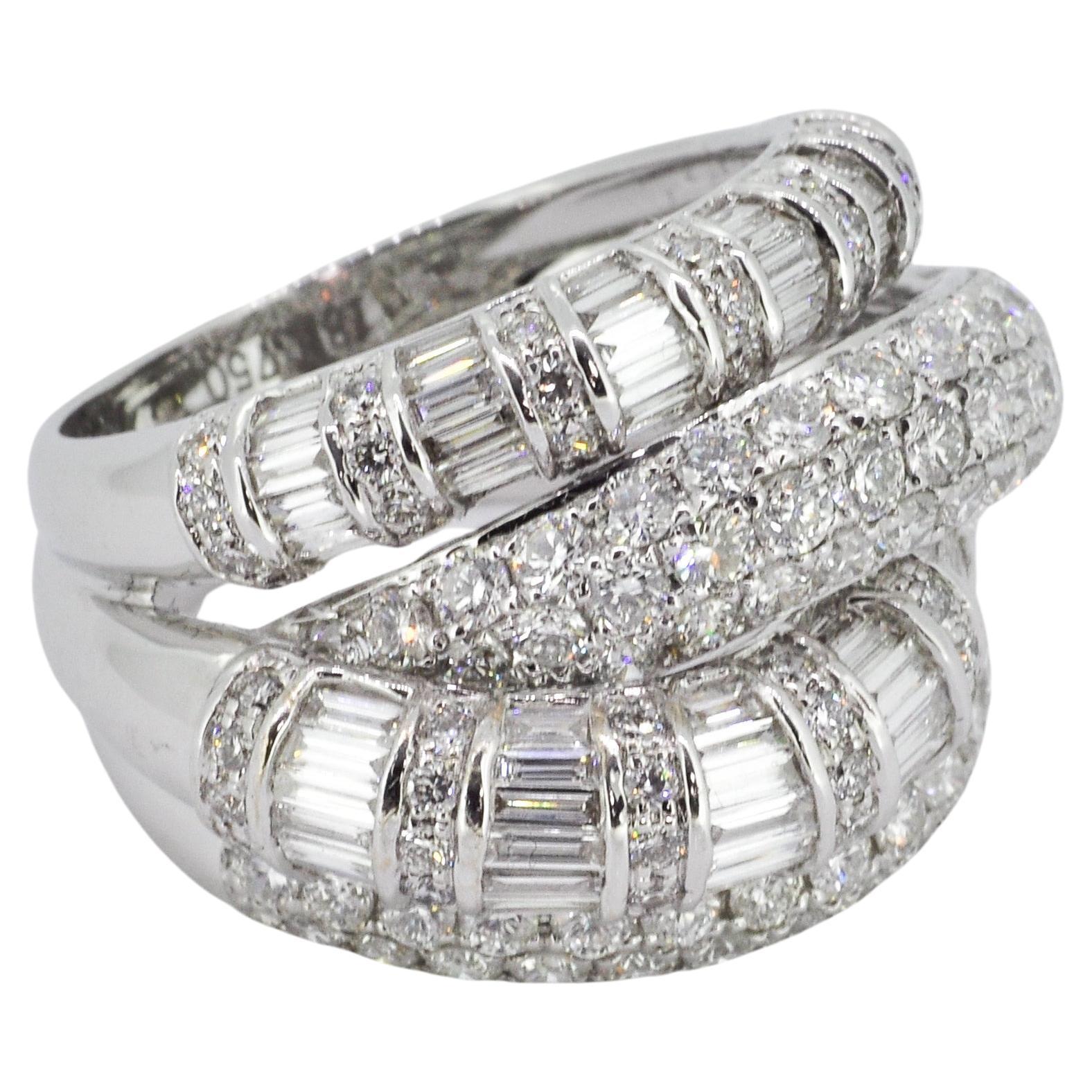 Cette bague en or blanc est un véritable témoignage de l'art de la conception de bijoux. Fabriqué en or blanc 18 carats, il présente un sertissage audacieux de diamants ronds et baguettes qui attirent la lumière sous tous les angles. Avec un poids