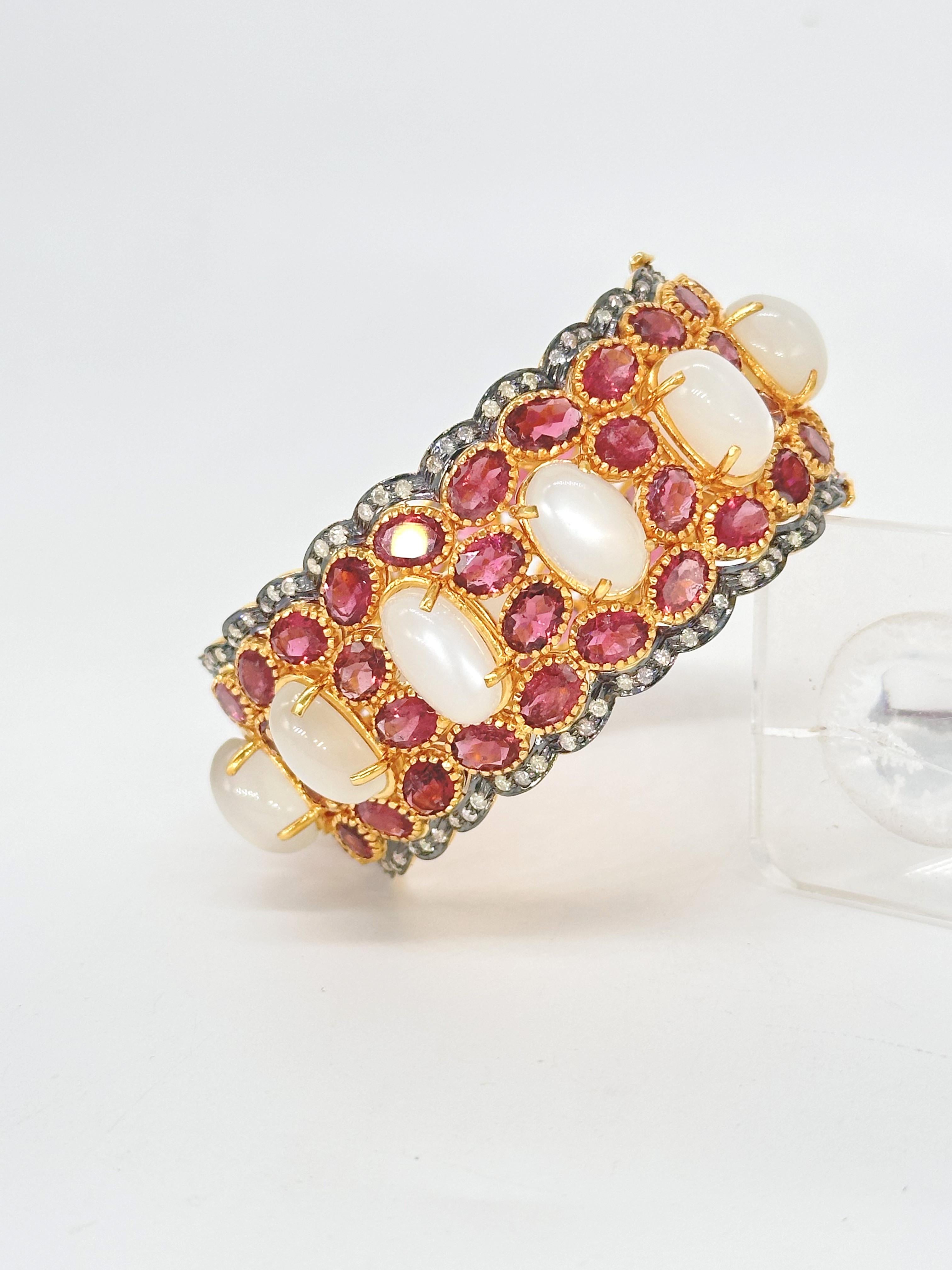 SKU-50PUJ-EU/VA
Add a touch of luxury to your jewelry collection with this magnificent broad 18K gold-plated hinged bangle bracelet. Crafted from sterling silver, this stunning piece is adorned with natural rubellite and moonstone gemstones,