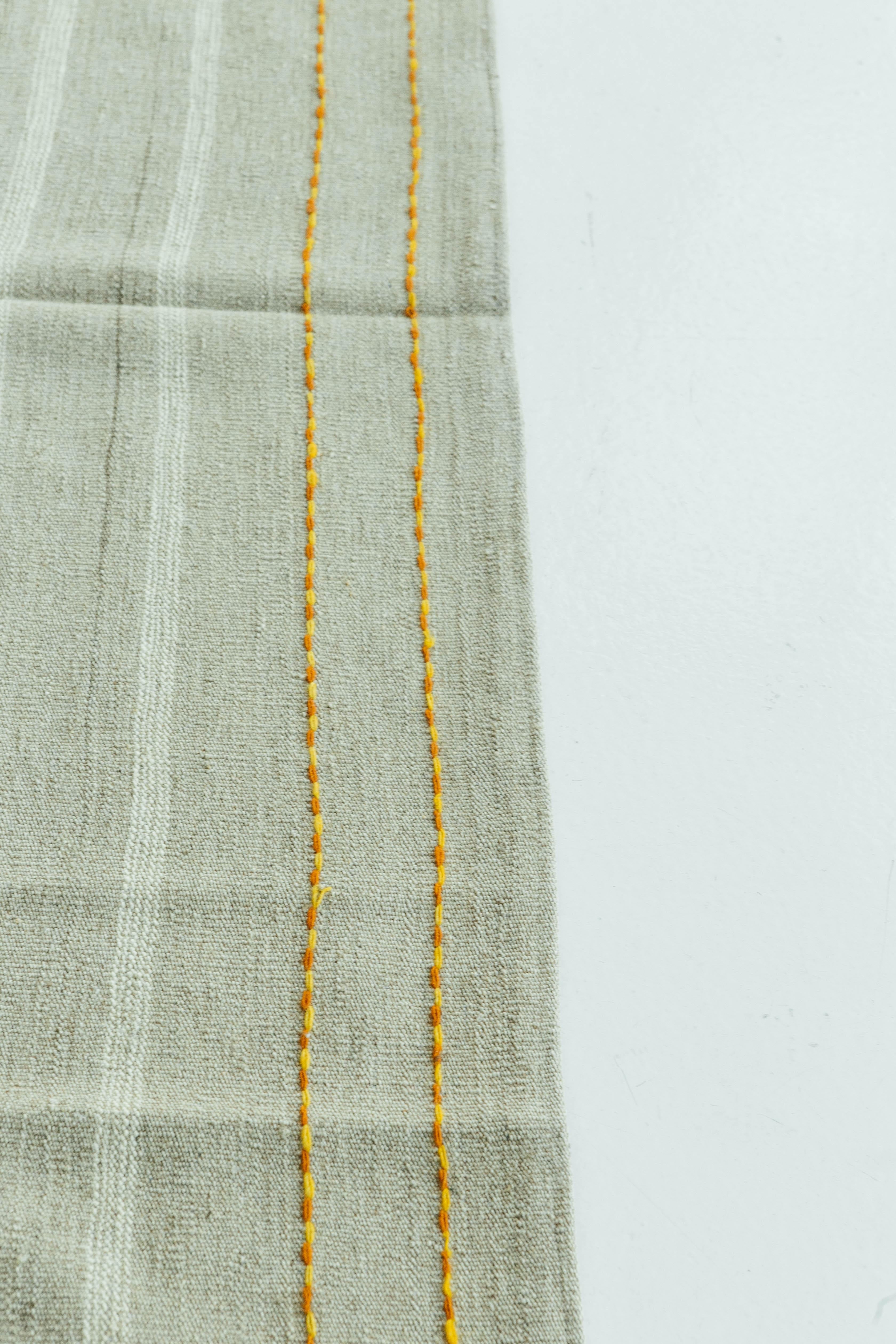 Natural taupe and ivory banded flat-weave in an alternating stripe pattern. Red and yellow detailing run across the top and bottom and add a touch of vibrancy. The Puro collection features contemporary designs handmade by skilled artisans in