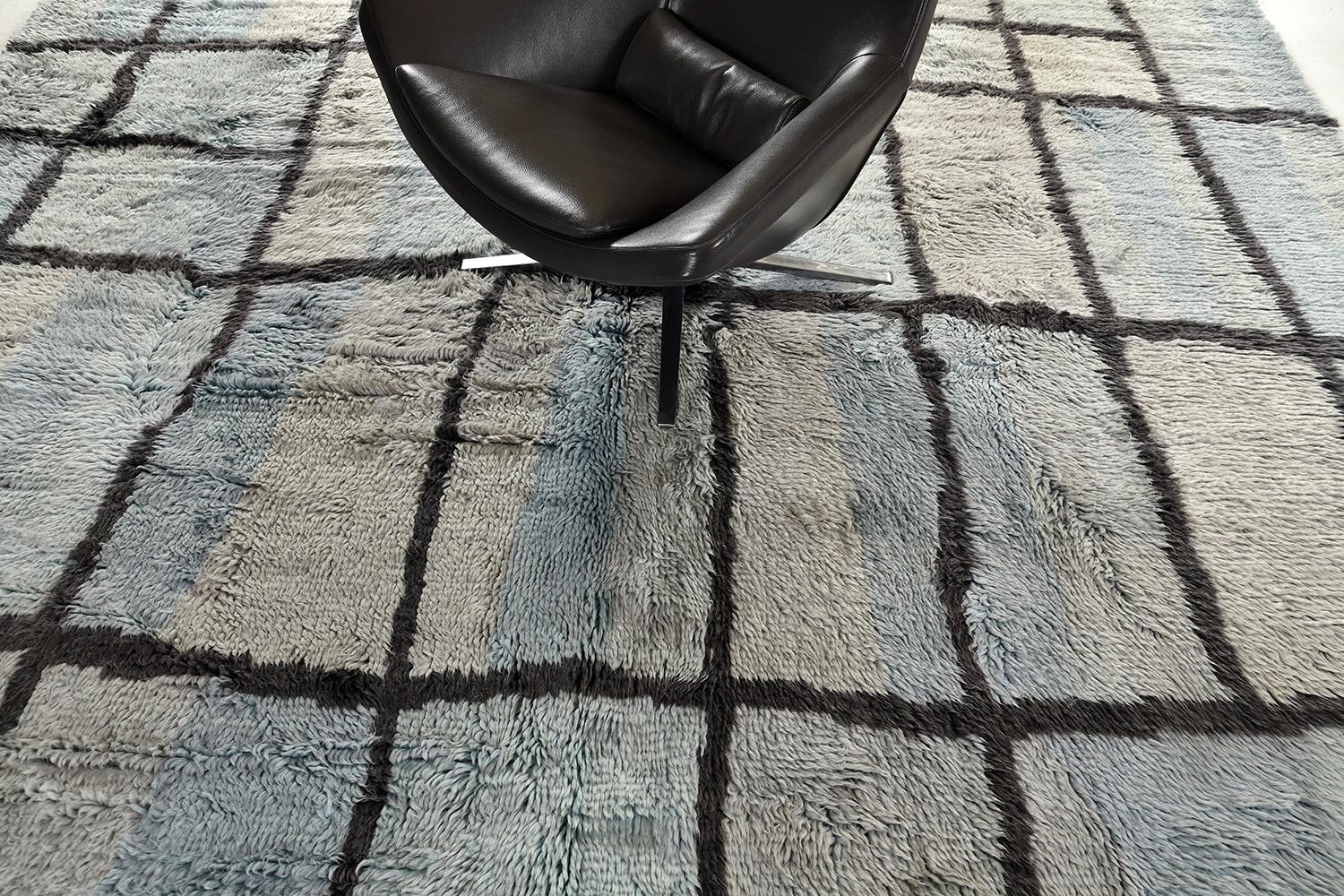 Bahja is an elegant hand-spun wool shag that features a solid irregular squared pattern over blue and gray schemes. Impressive tassels are woven with a grace that makes the pattern more interesting. A perfect masterpiece for the modern