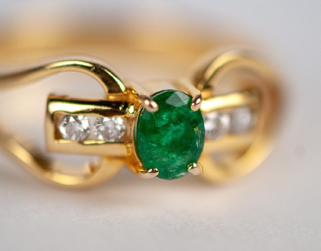 Cette magnifique bague présente en son centre une émeraude naturelle de forme ovale, magnifiquement entourée de diamants naturels, le tout serti dans une monture en or jaune 18 carats. La bague est d'une taille approximative de 5,5. 