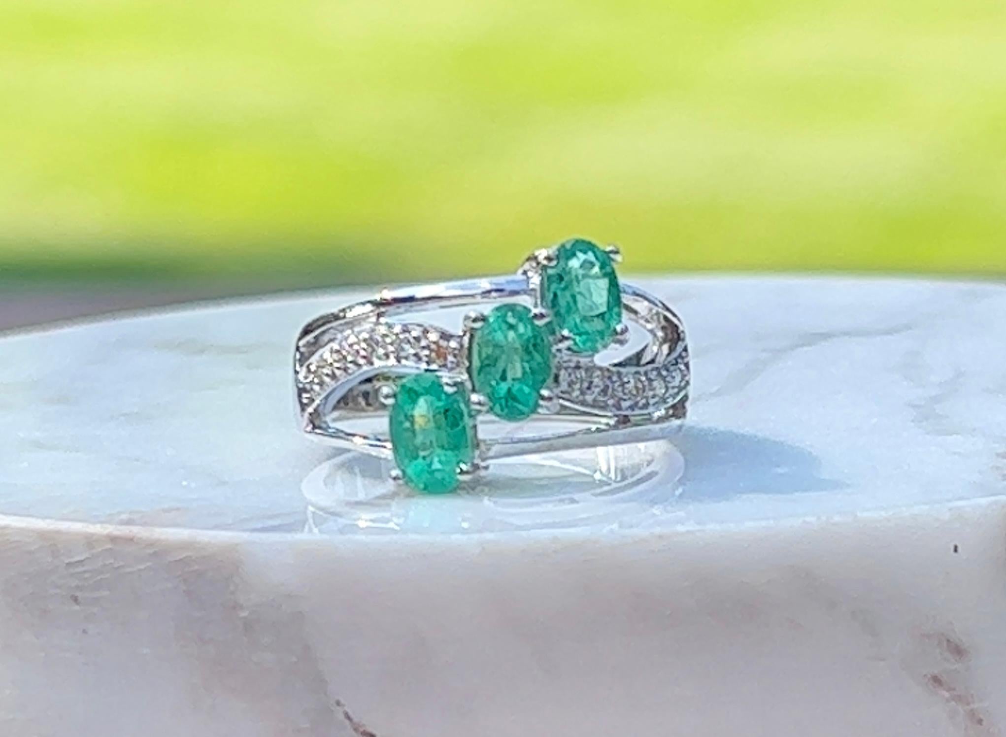 One 18-karat white gold ( stamped 18K) split shank design ring set with three (3) 6x4mm natural oval emeralds, approximately 1.50-carat total weight, and ten (10) round brilliant cut diamonds, approximately 0.15-carat total weight with matching H/I