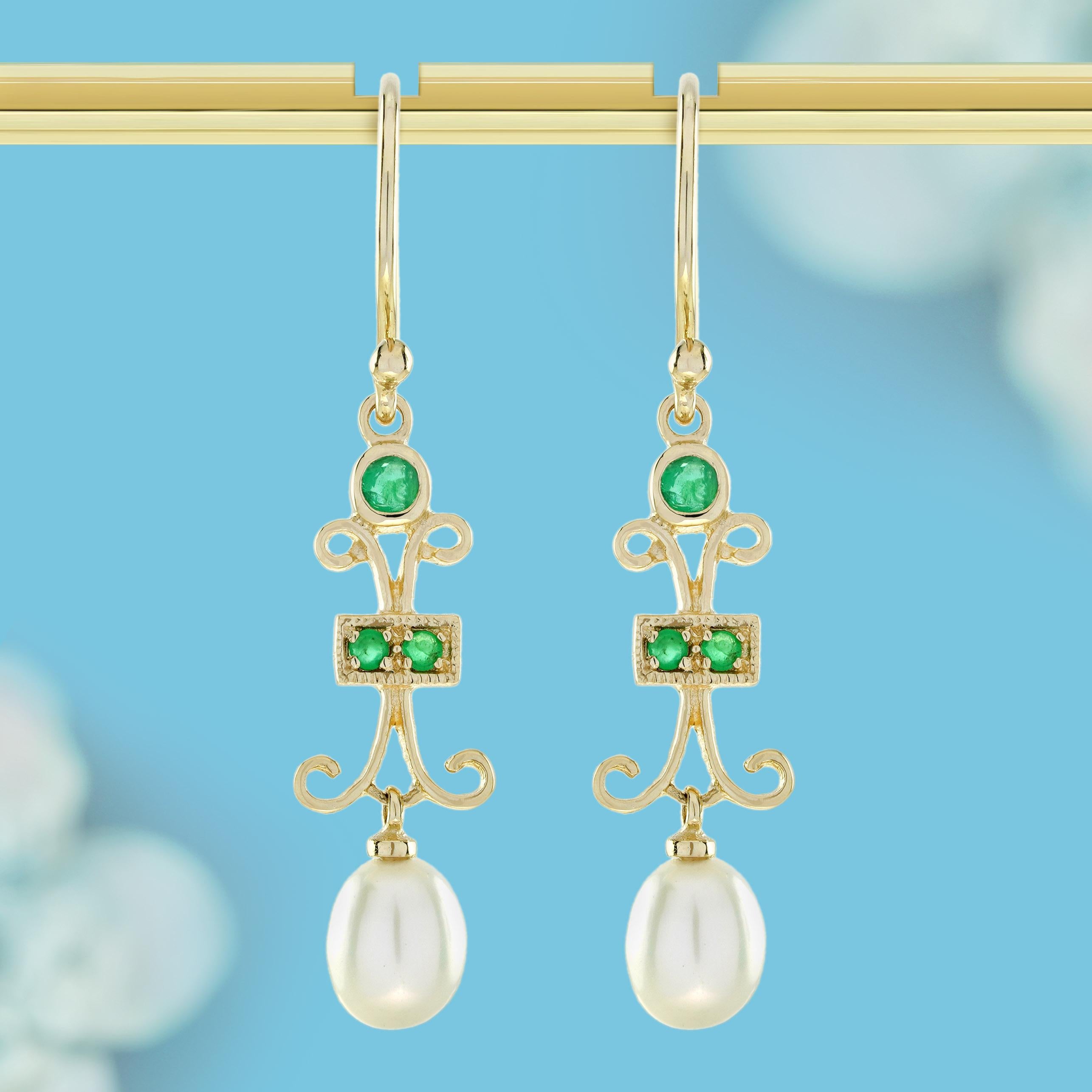 These earrings are true vintage-inspired treasures. Each exquisite piece showcases a regal square emerald cradled in a radiant gold embrace, suspended between delicate white pearls arranged in intricate leaf-like frames above and below. Dangling