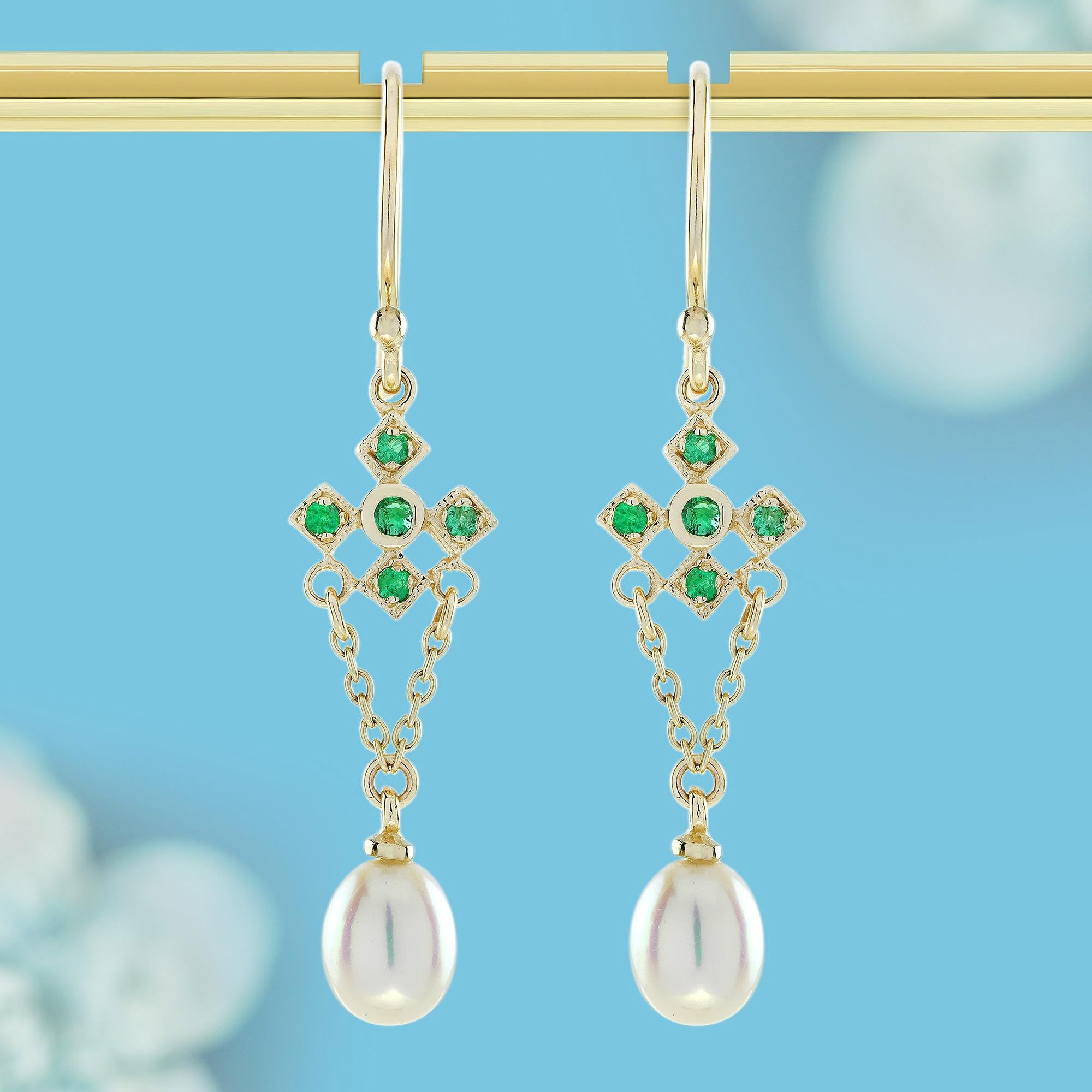 Estos  par de pendientes de esmeraldas de inspiración vintage presenta deslumbrantes racimos de esmeraldas que brillan dentro de ornamentados engastes de oro, evocando una sensación de lujo y refinamiento. Delicadas perlas blancas de agua dulce caen