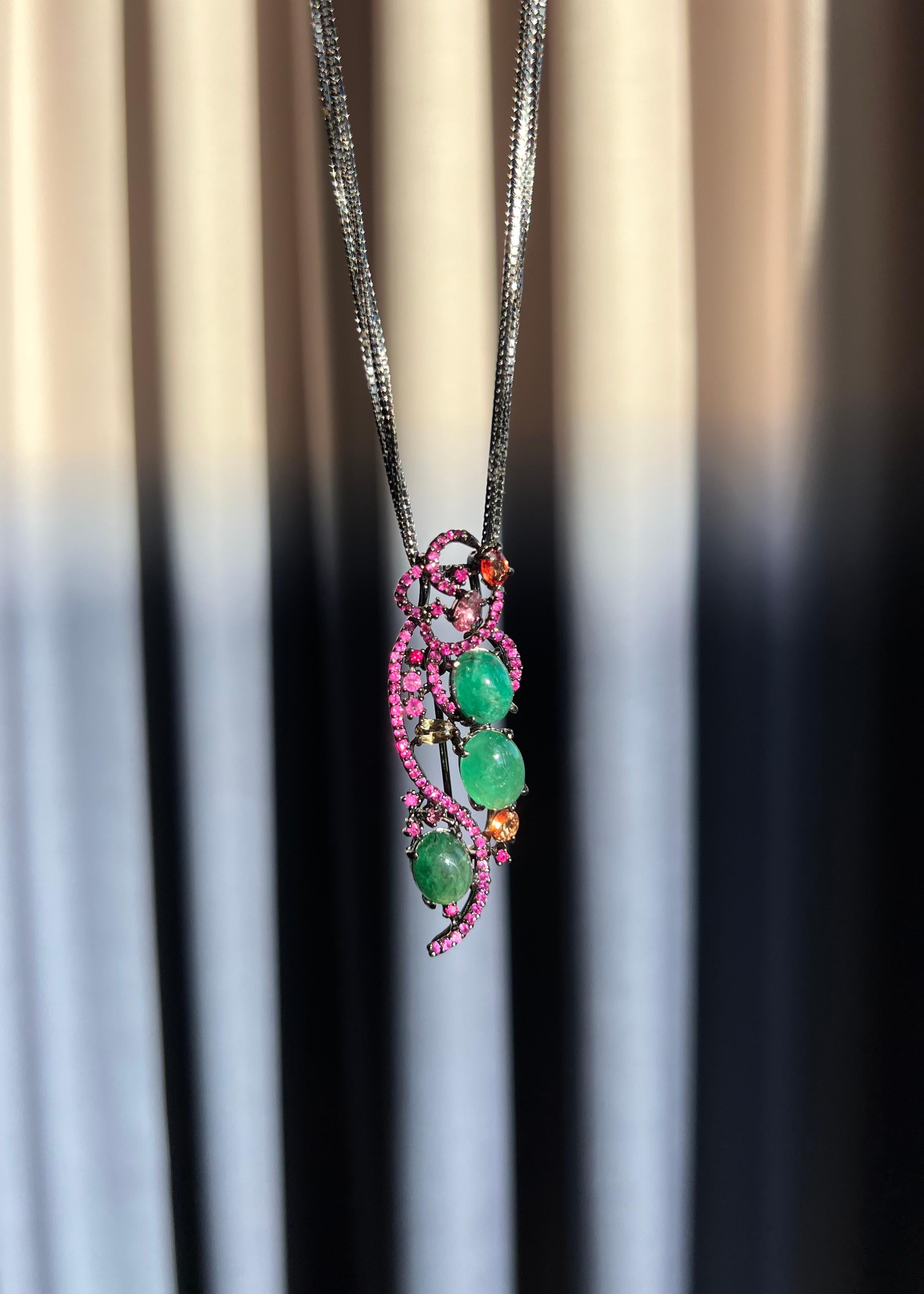 This versatile and unique piece can be worn as a pendant or brooch, adding a touch of luxury to any outfit. Featuring stunning natural cabochon emeralds, rubies, orange sapphires, and tourmaline, this piece is both elegant and edgy, making it a true