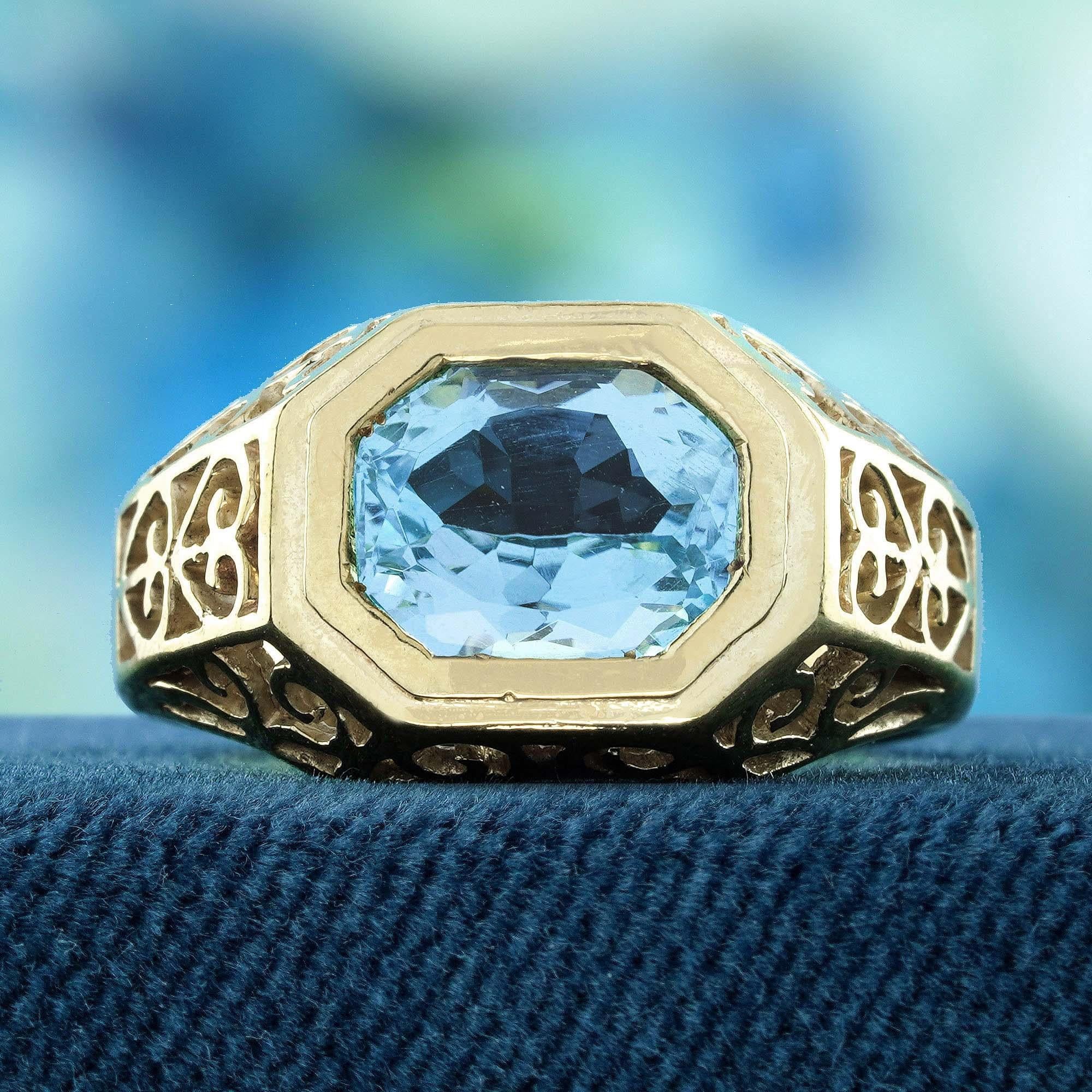 Embrace timeless elegance with this natural blue topaz antique style filigree ring in solid yellow gold. Featuring a stunning emerald cut blue topaz, this exquisite ring showcases intricate heart motif filigree work on both shoulders. The unique