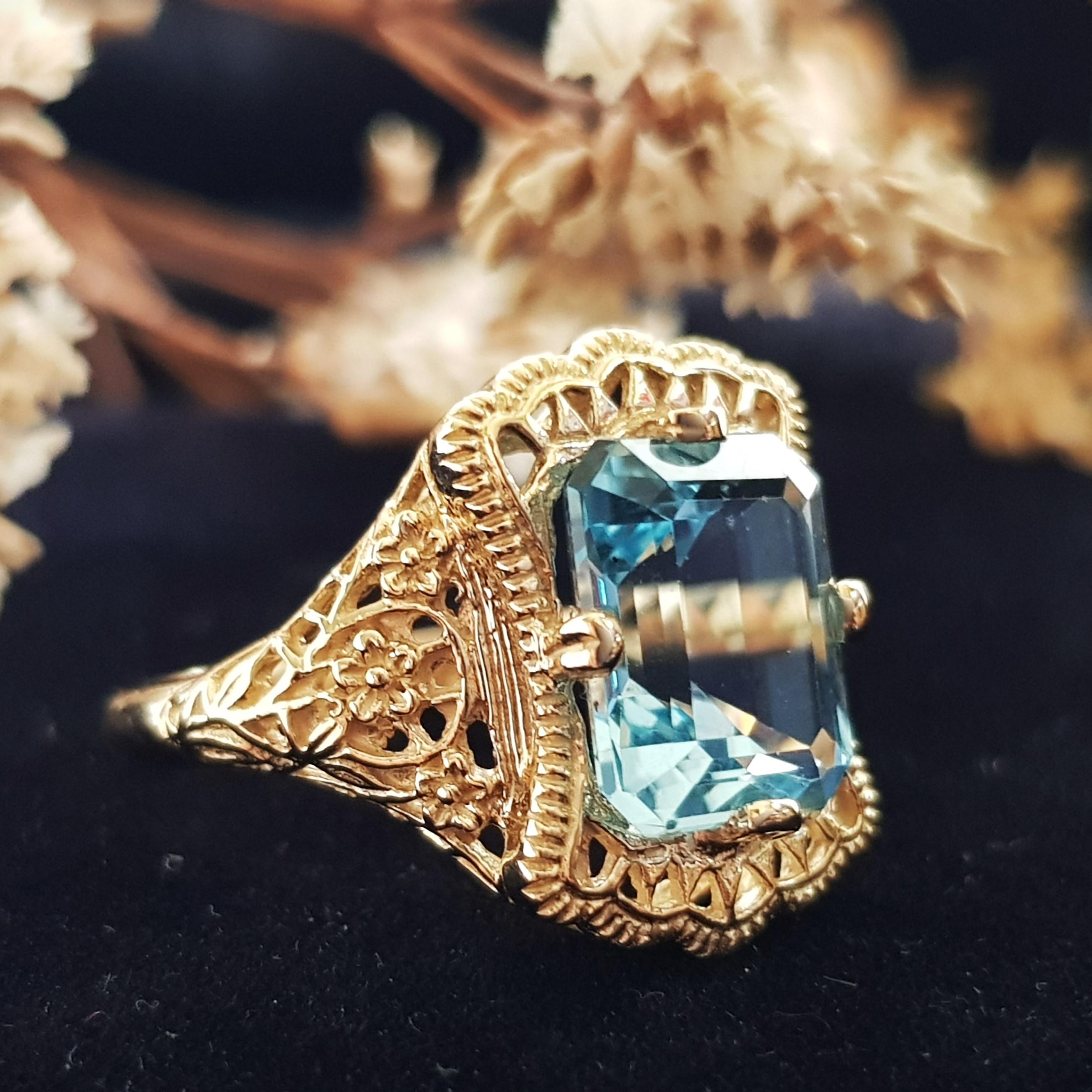 An Art Deco style filigree ring with 4.5 carats natural emerald cut blue topaz in the center. Filigree rings are timeless in style and can be enjoyed, cherished and handed down as precious family heirlooms.

Ring Information
Metal: 14K Yellow Gold –